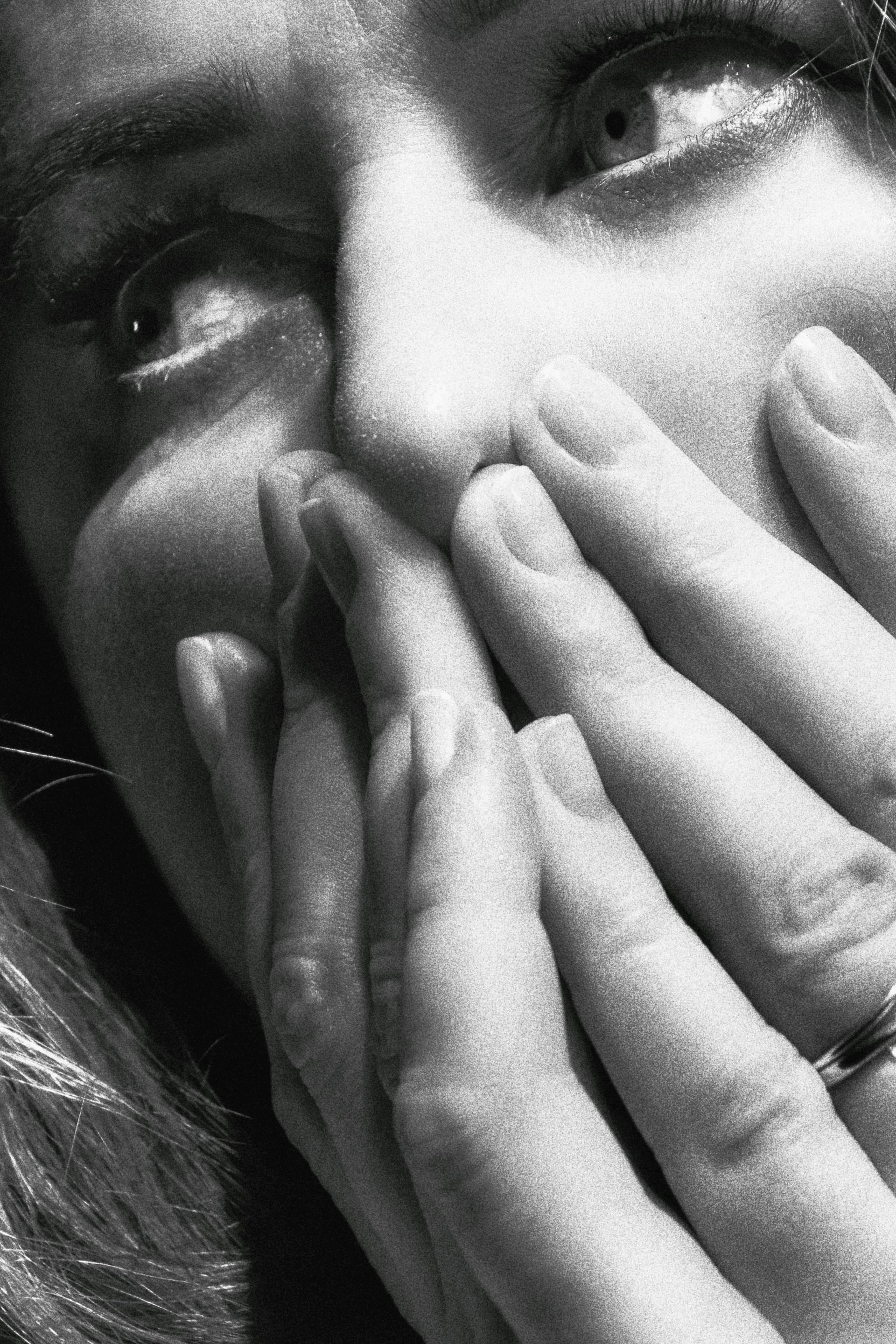 A grayscale photo of a woman covering her face with her hands | Source: Pexels