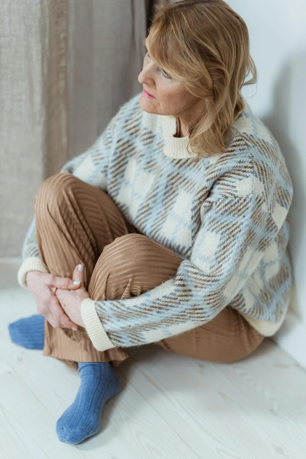 A middle-aged woman sitting on the floor | Source: Pexels