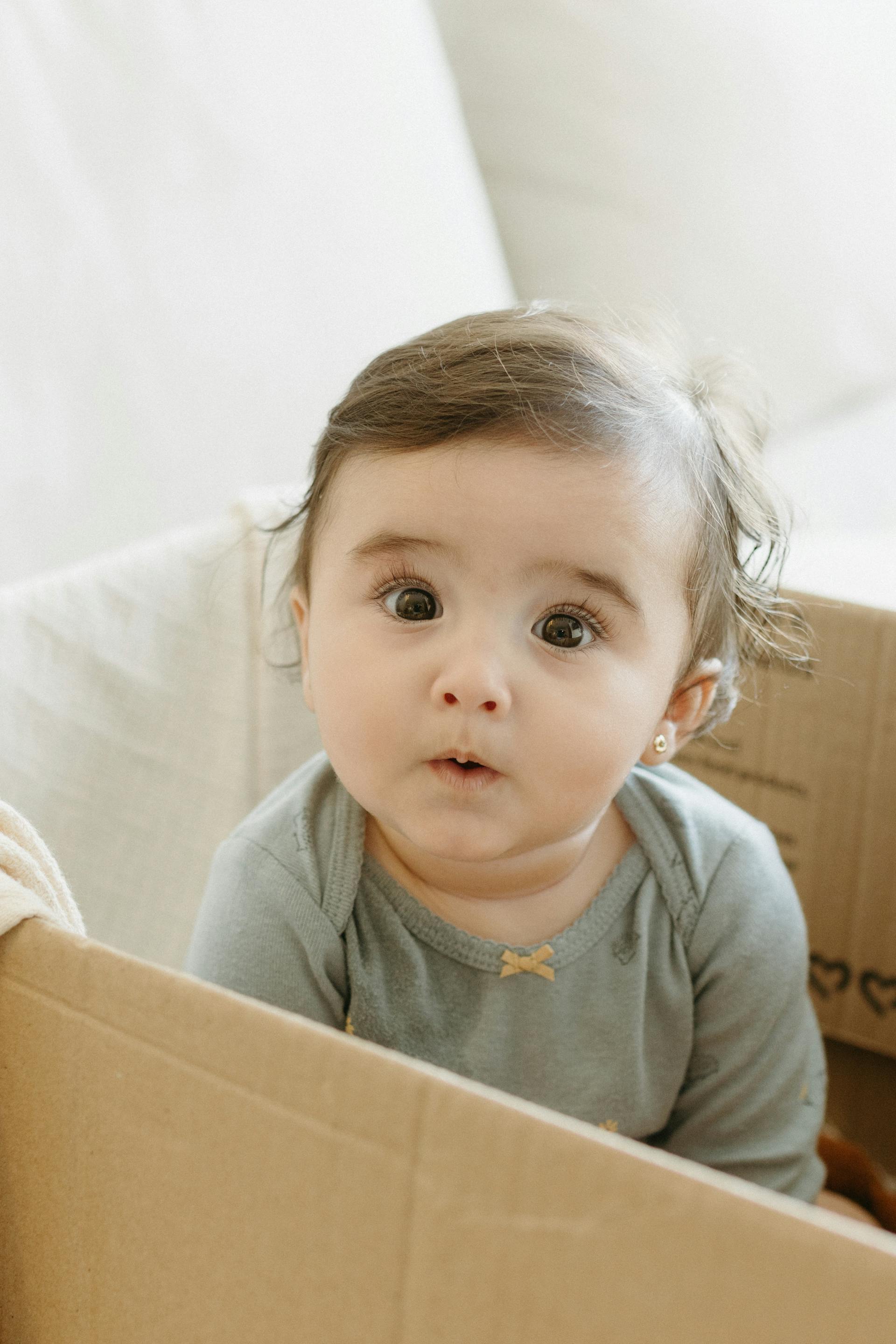 A little girl sitting in a box | Source: Pexels