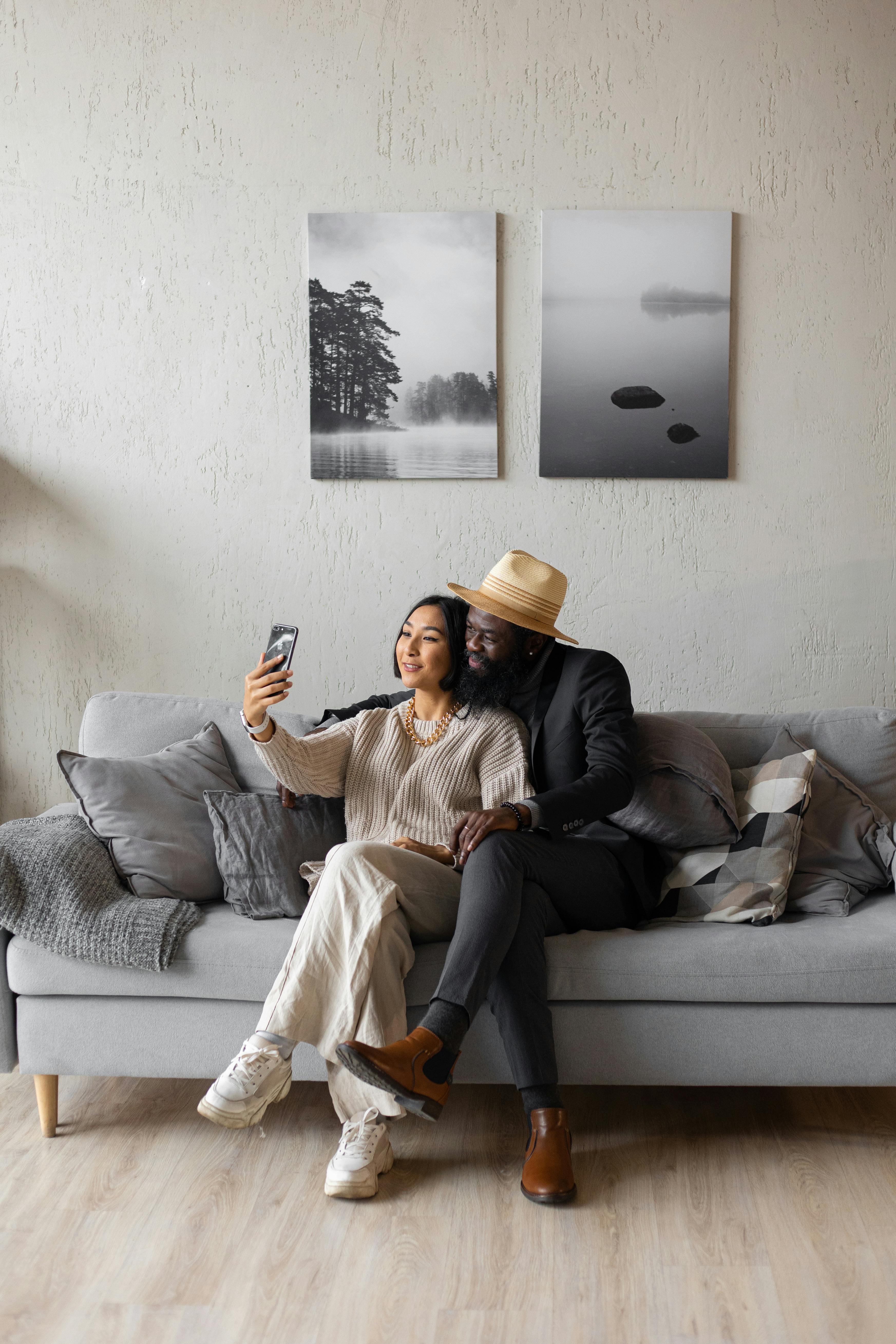 A couple taking a selfie on a couch | Source: Pexels
