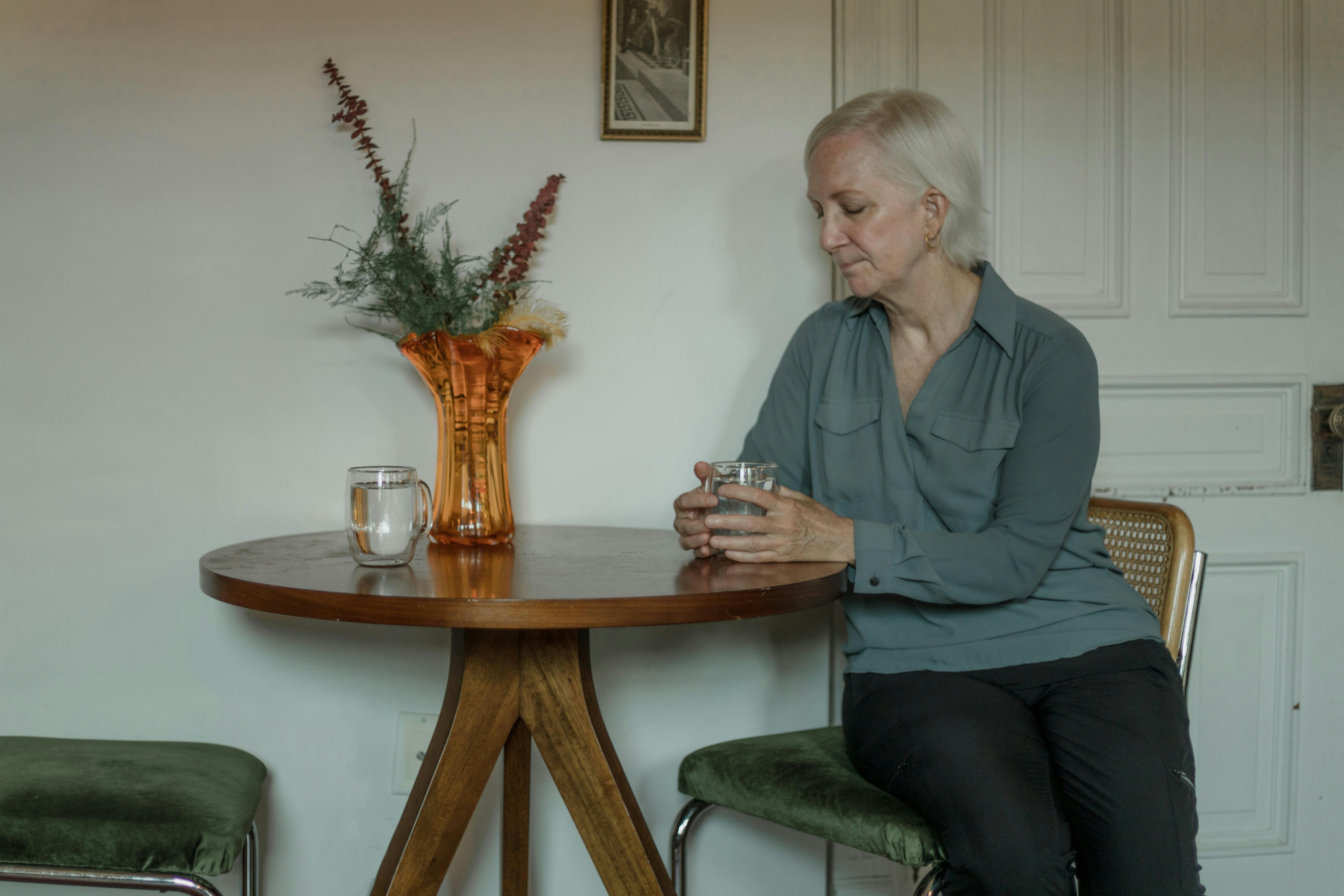 An elderly woman sitting at a table | Source: Pexels