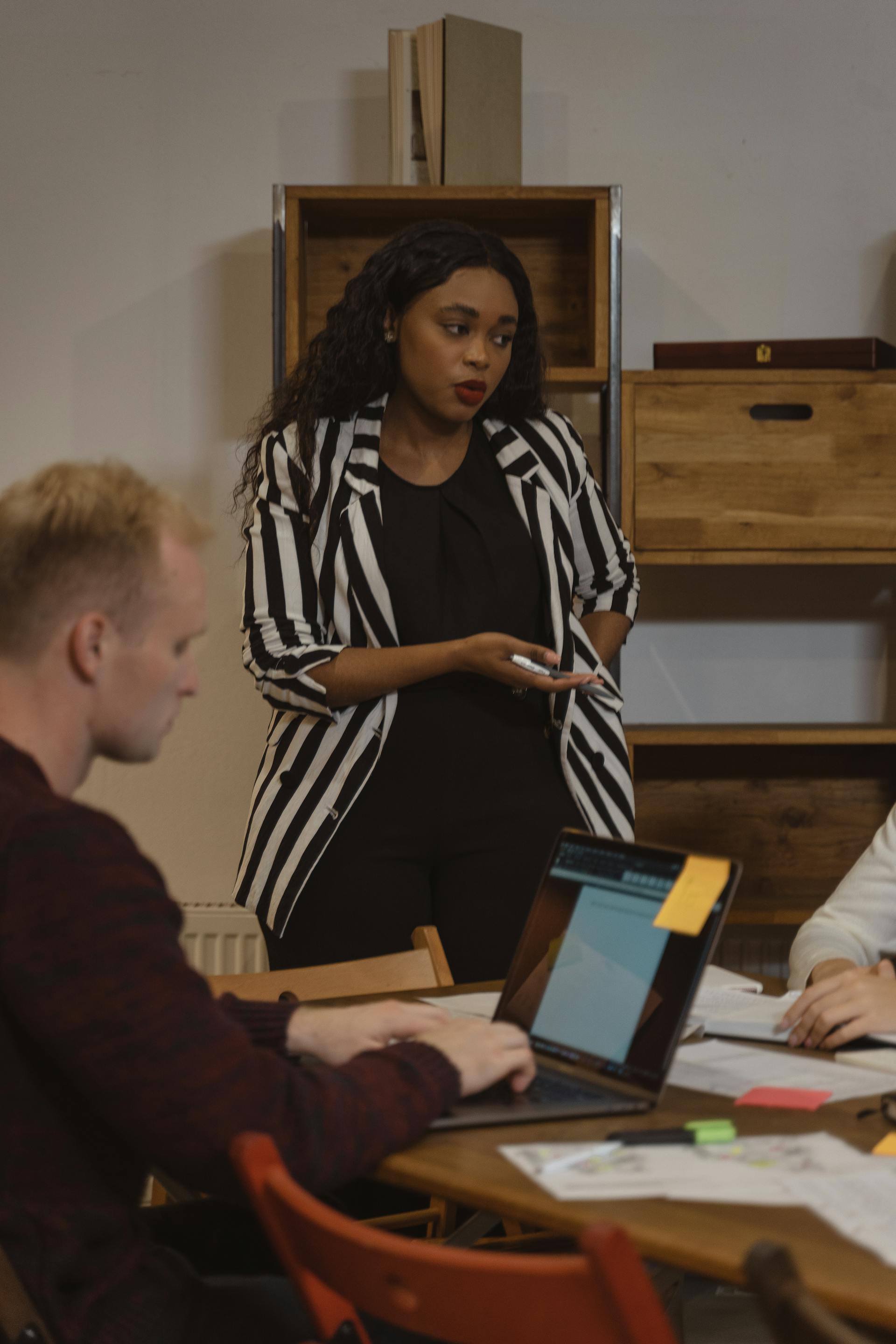 A woman frowning while talking to coworkers in a conference room | Source: Pexels