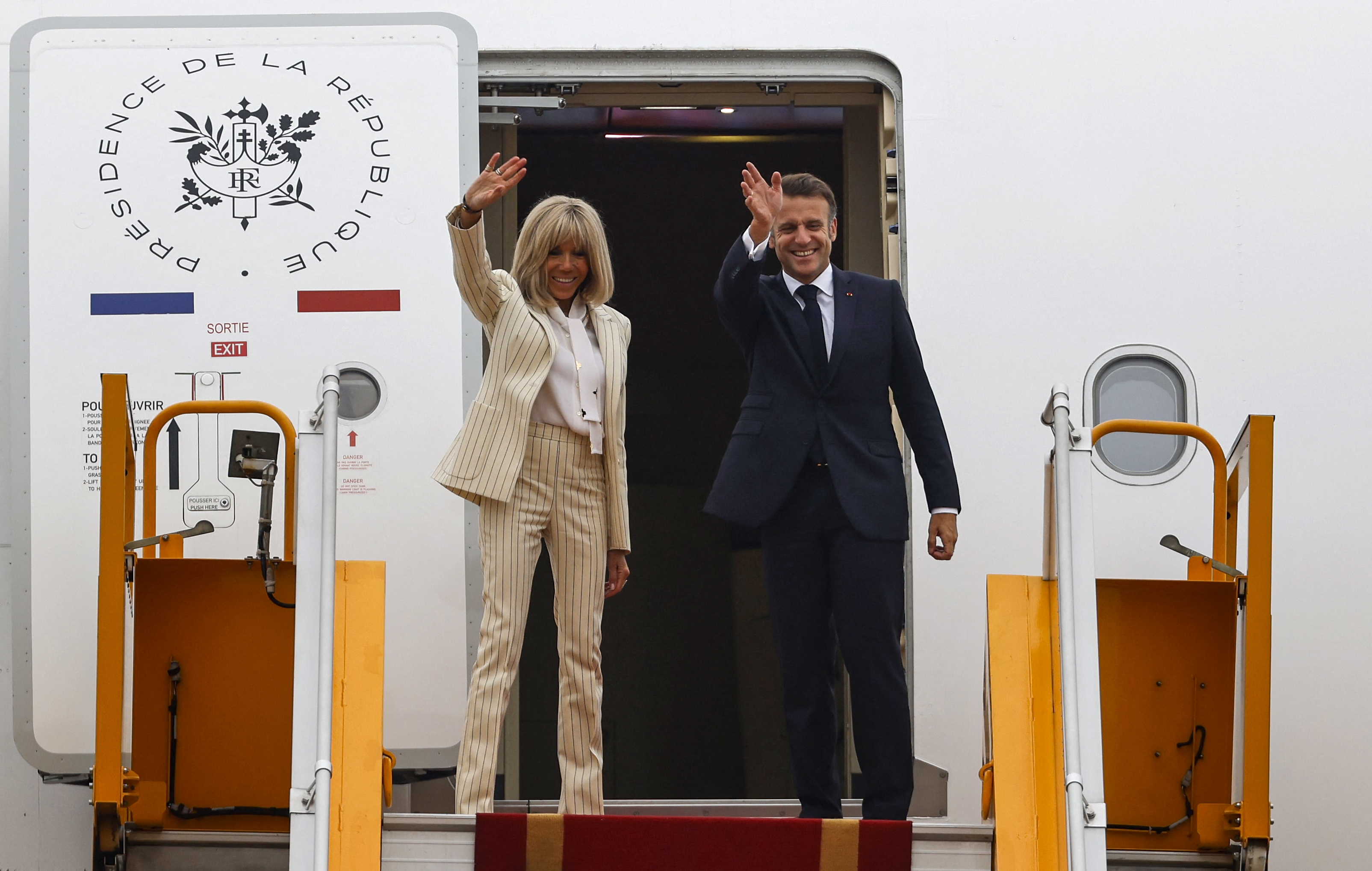 France's President Emmanuel Macron and his wife Brigitte Macron wave as they board their plane for departure following their visit to Vietnam at Noi Bai International Airport in Hanoi on May 27, 2025. | Source: Getty Images