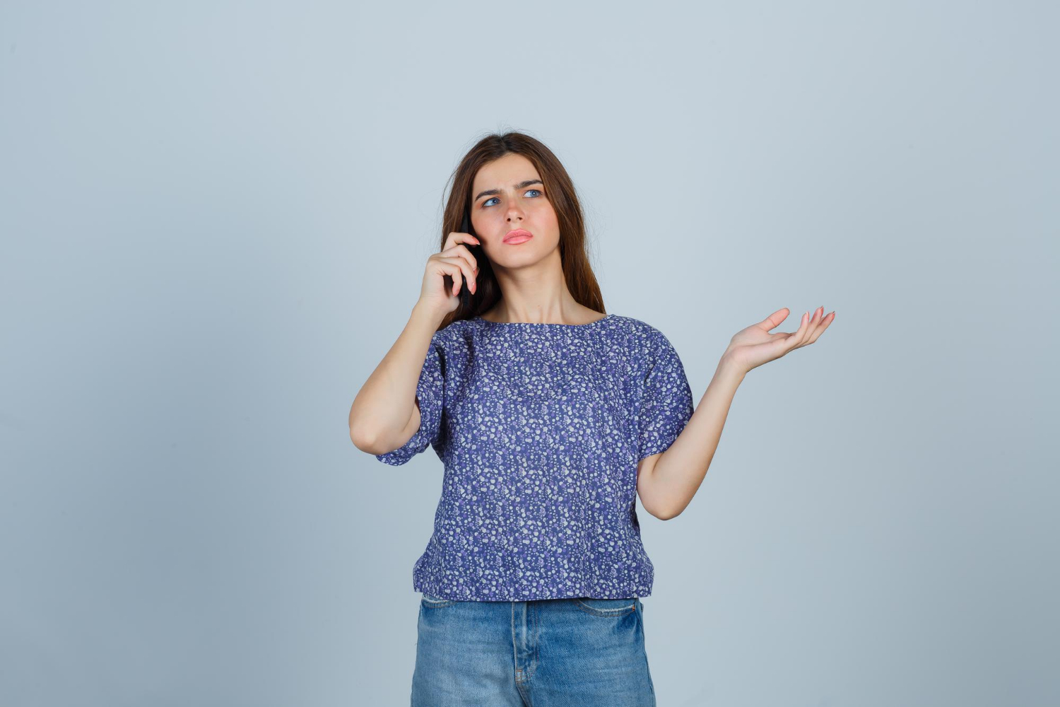 A disheartened young woman talking on the phone | Source: Freepik