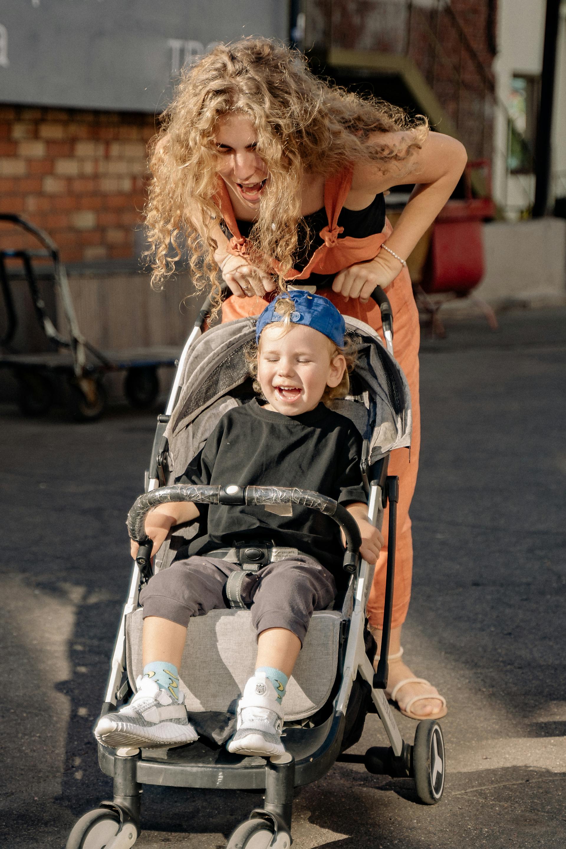 A woman having fun with her son in a stroller | Source: Pexels