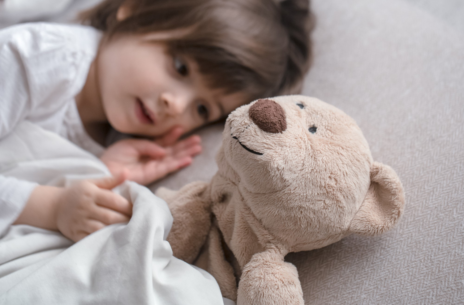 A little girl lying beside her teddy bear | Source: Freepik