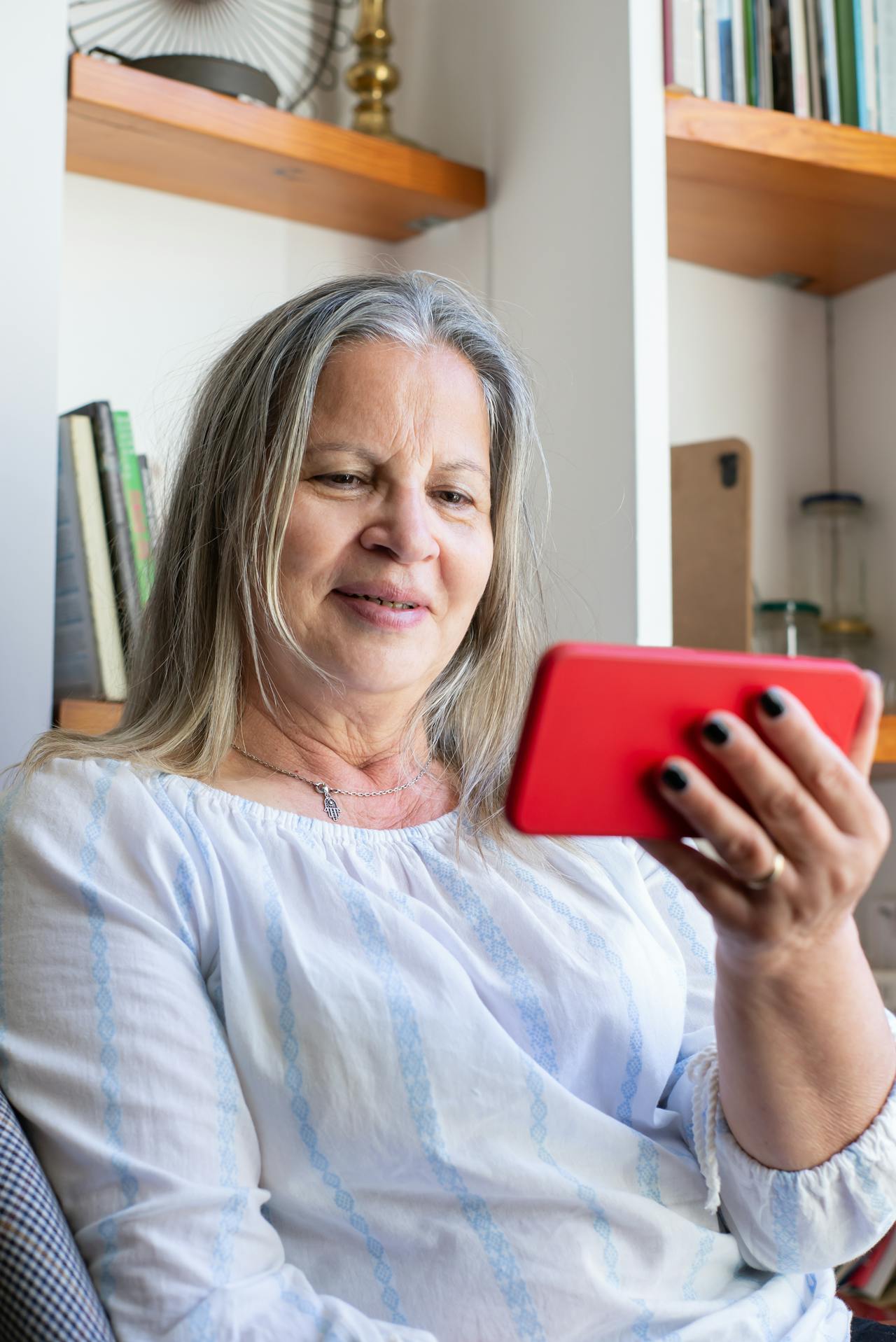 A senior woman looking at her phone and smiling | Source: Pexels