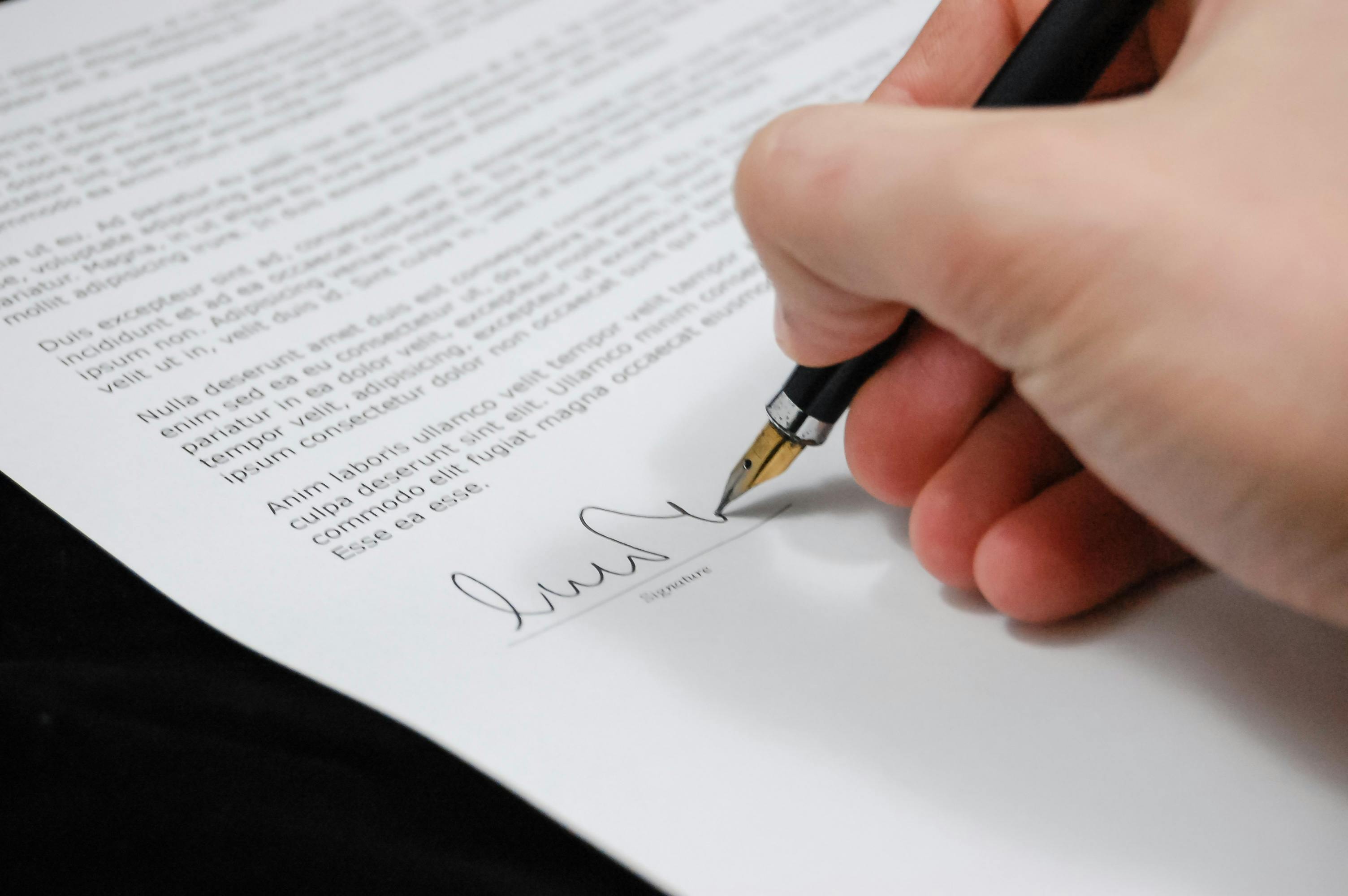 A person signing paperwork | Source: Pexels