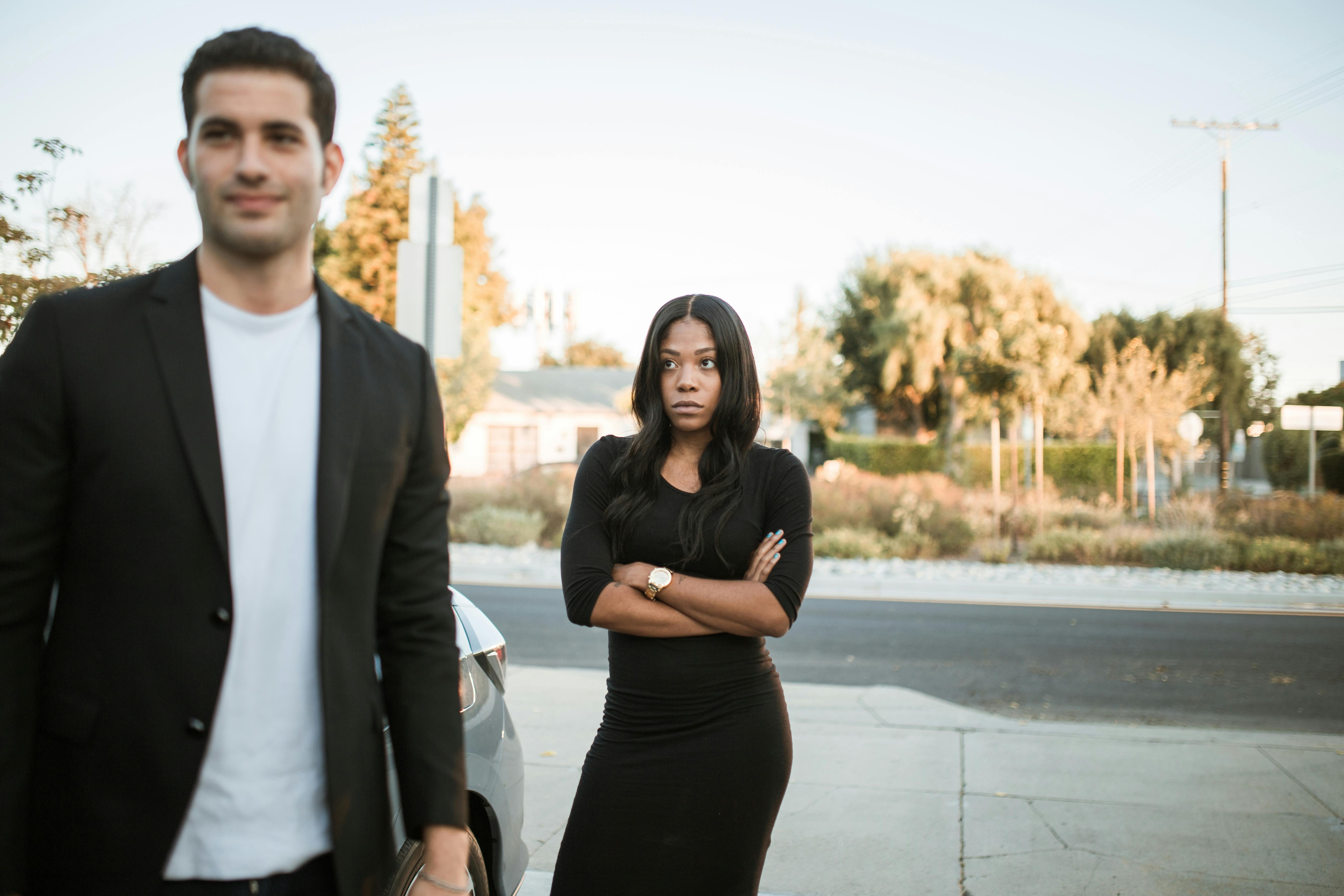 A smiling man standing in front of an upset woman | Source: Pexels