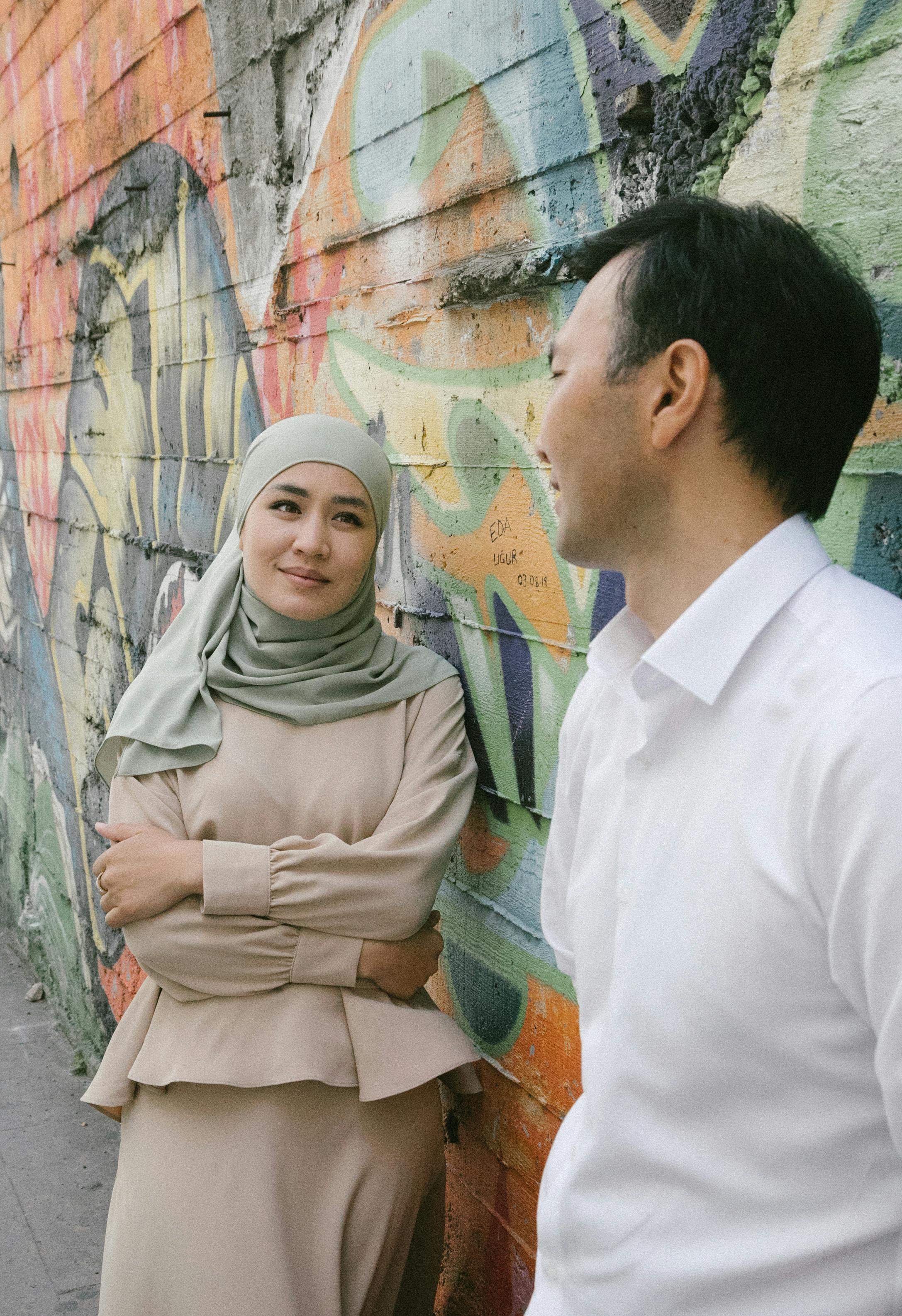 Woman looking at a man while standing next to a graffiti wall | Source: Pexels
