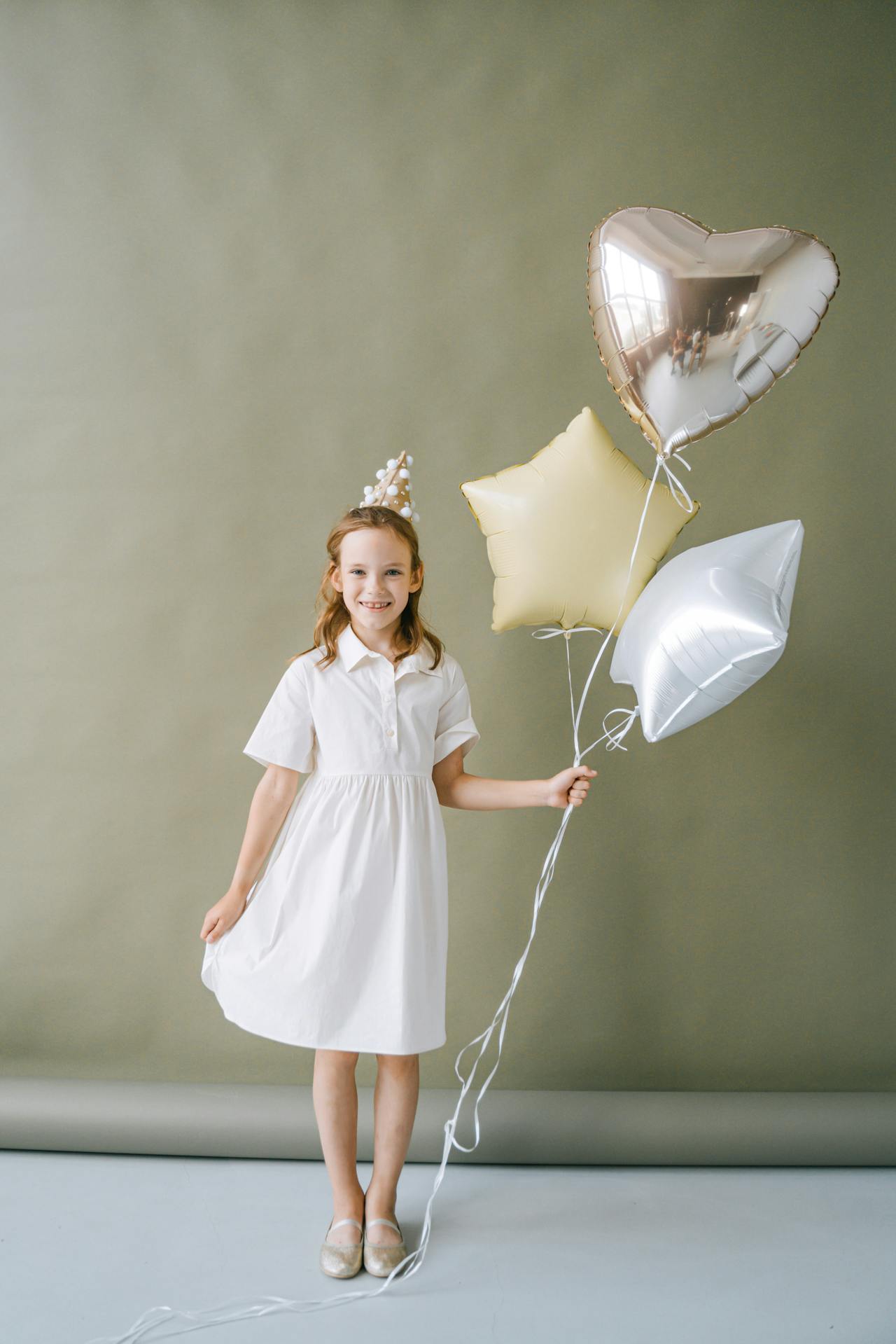A delighted young girl holding balloons | Source: Pexels