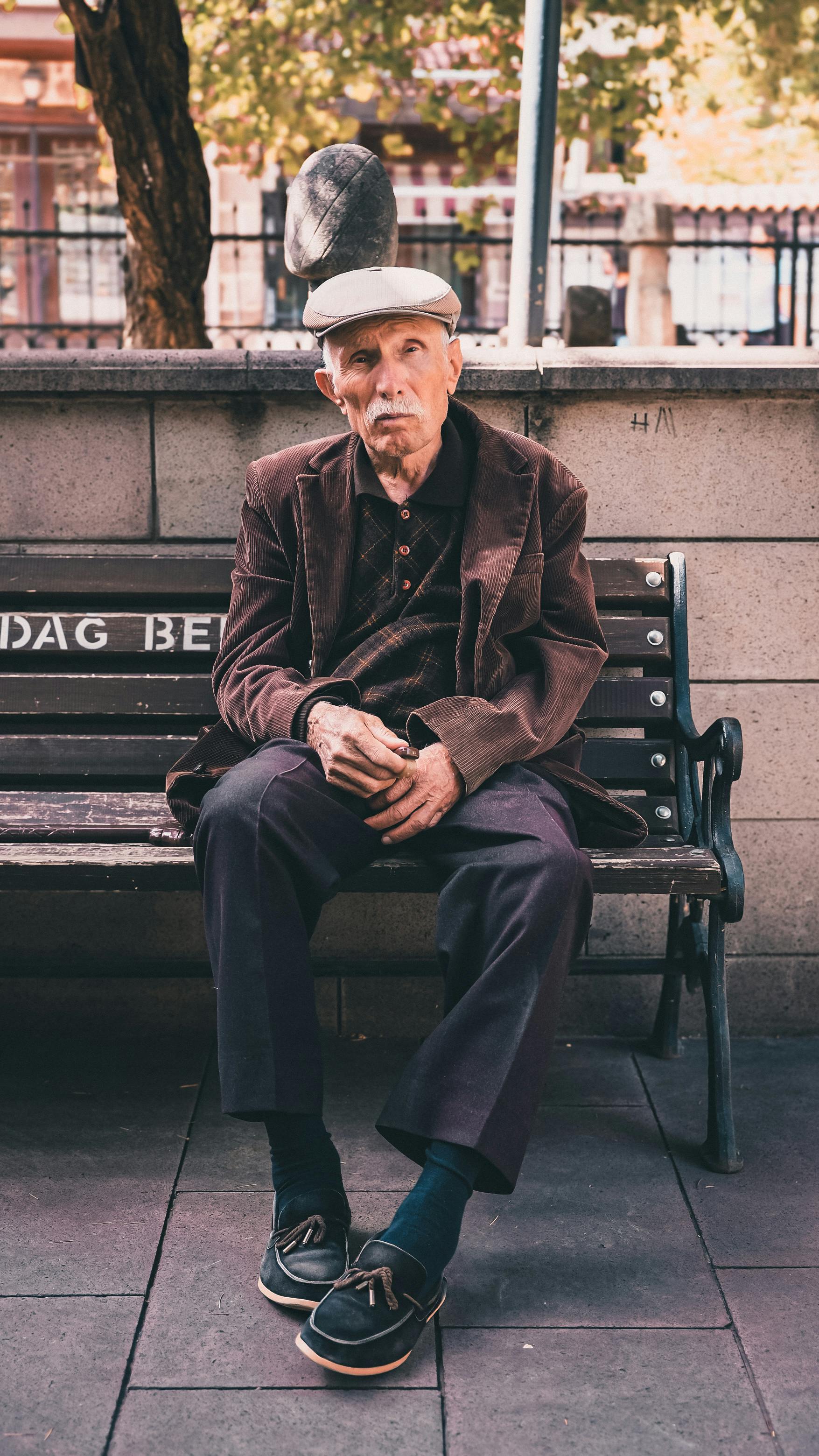 Um homem idoso sentado em um banco | Fonte: Pexels