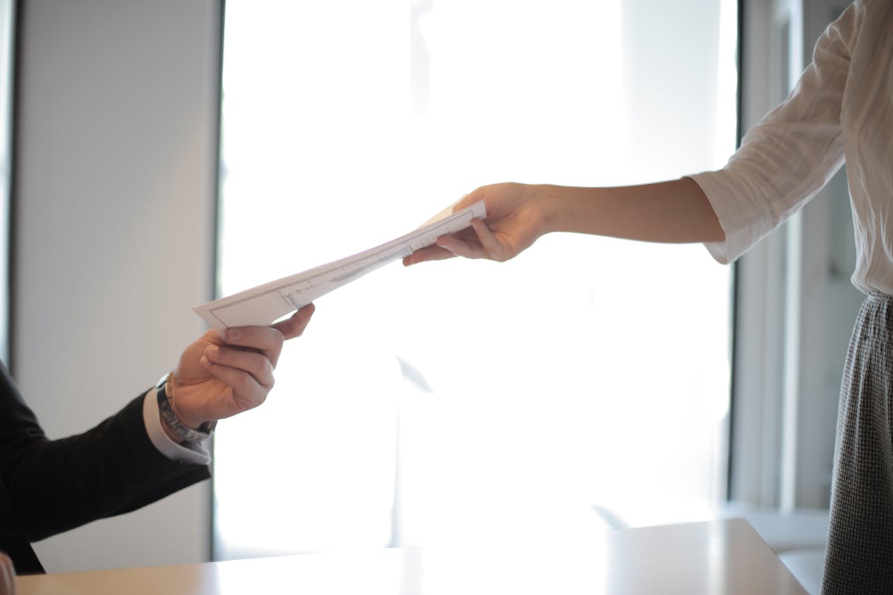 A man handing over papers | Source: Pexels