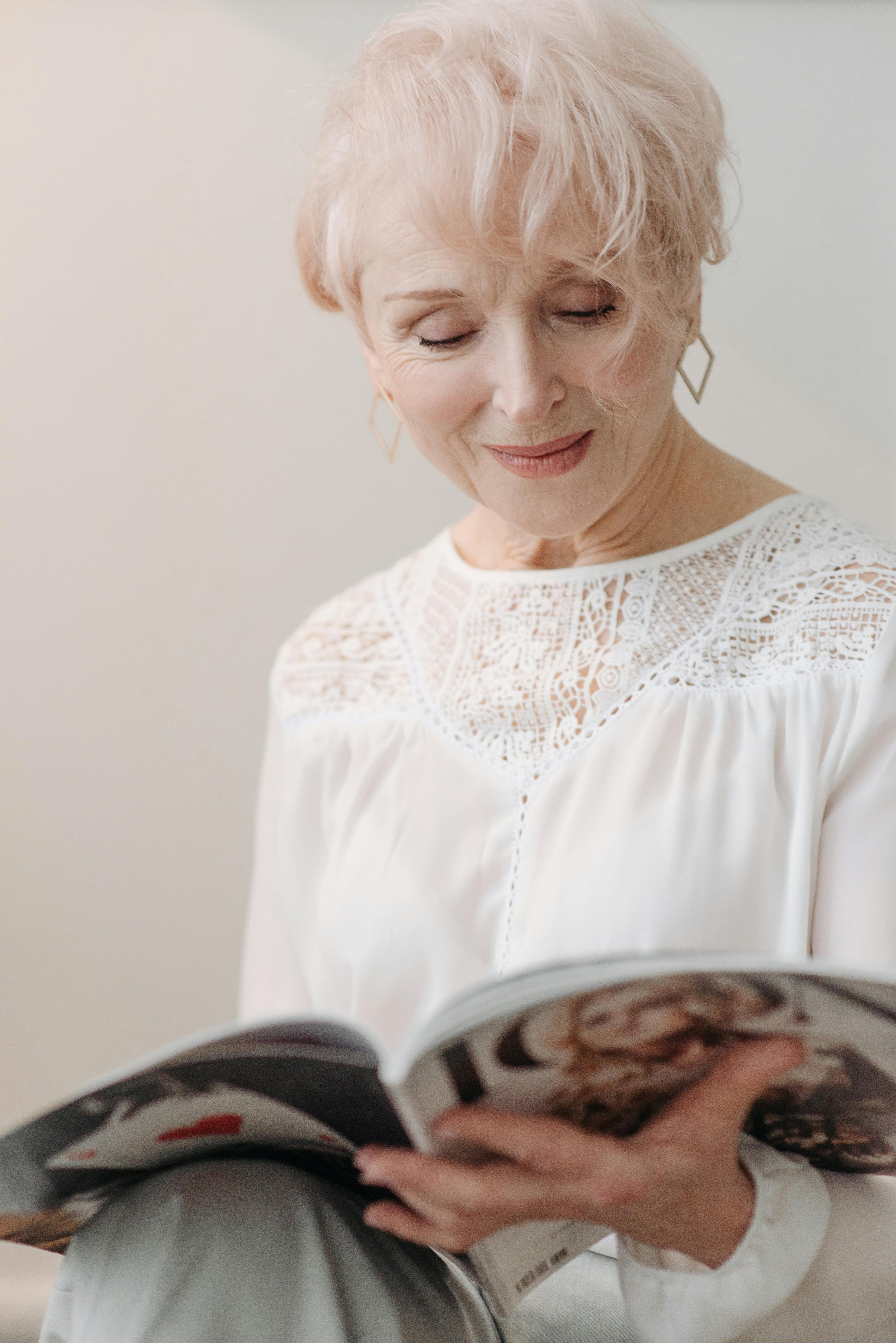 Uma mulher idosa sorridente lendo uma revista | Fonte: Pexels