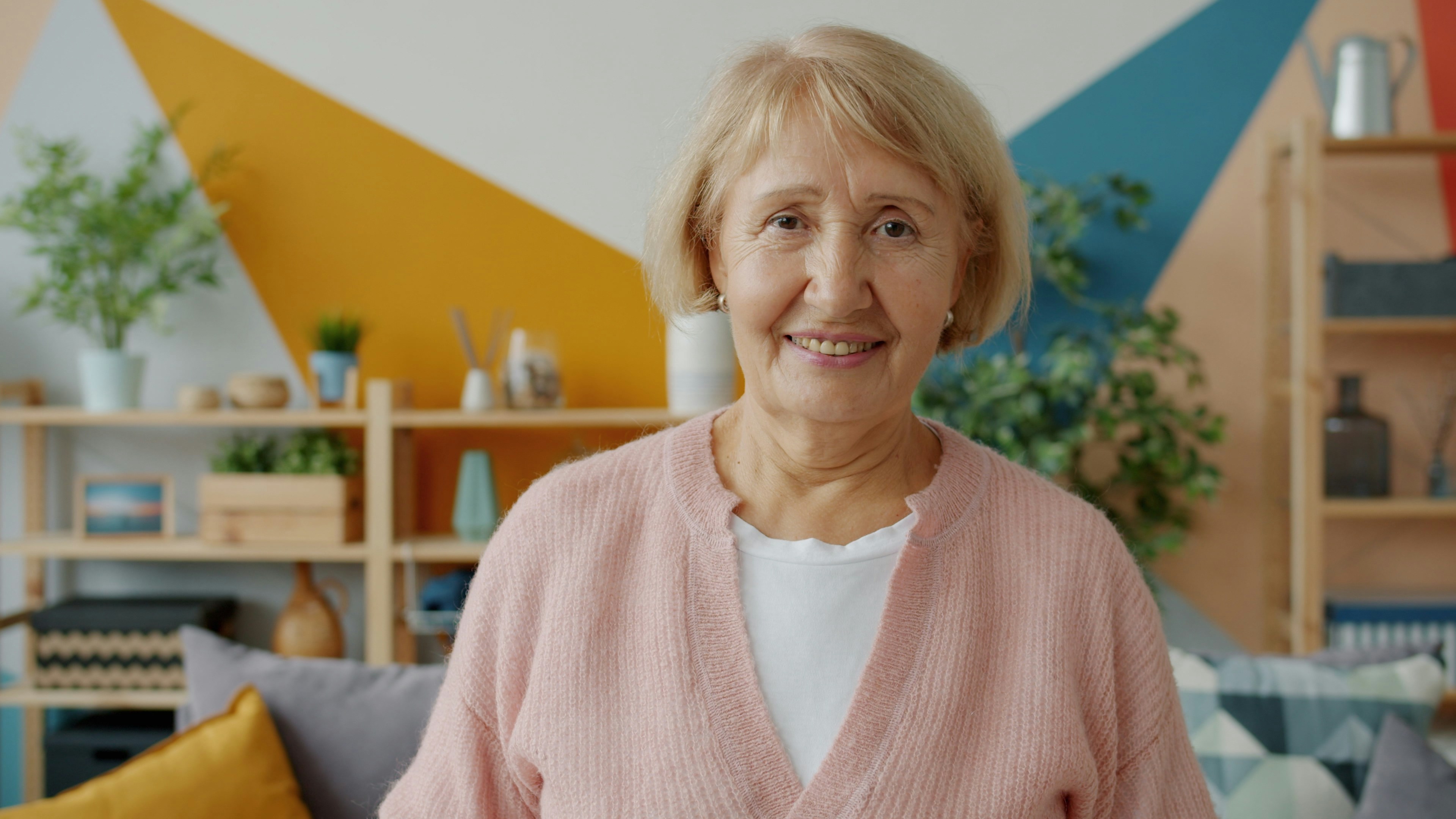 A smiling older woman in a pink cardigan | Source: Unsplash