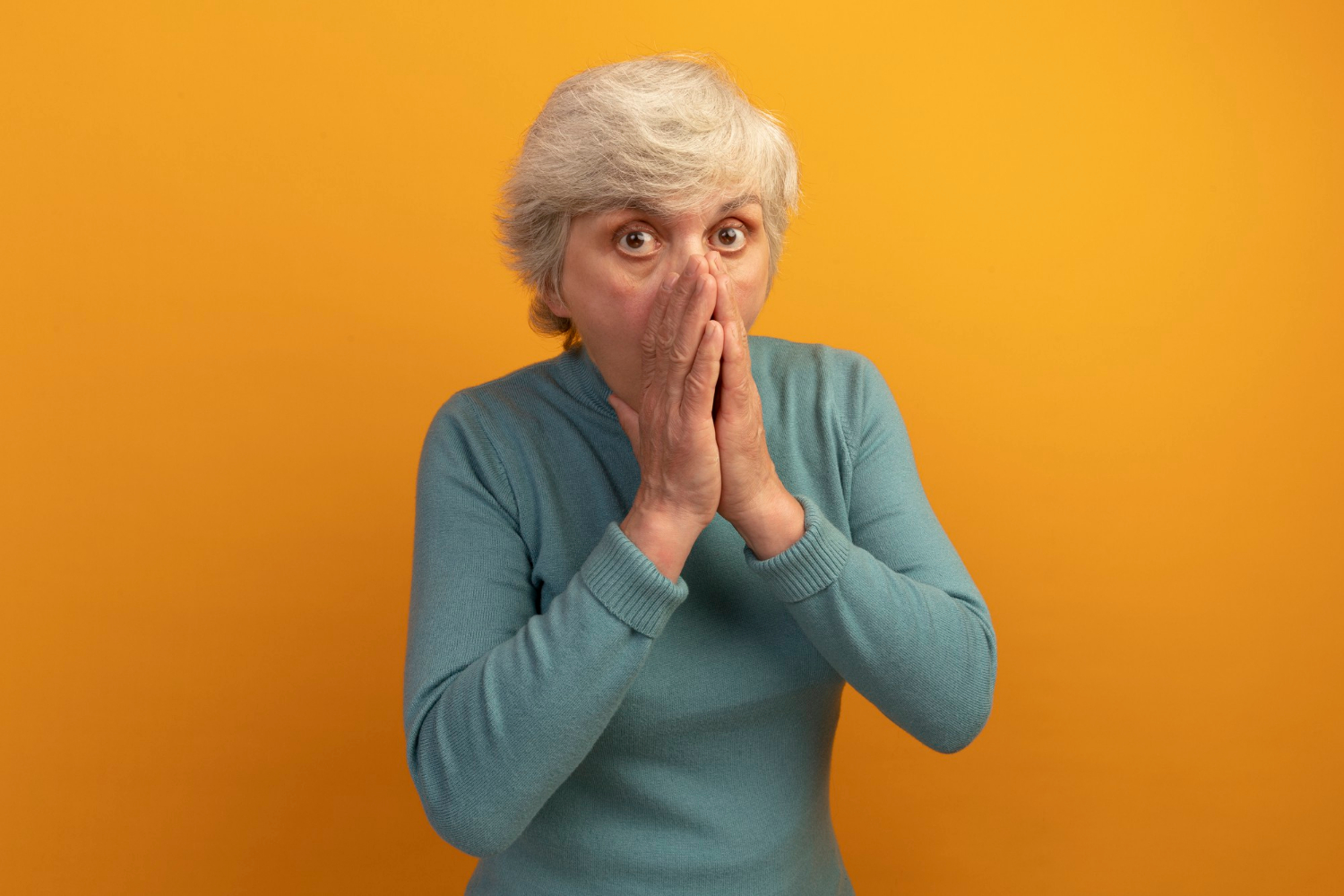 A shocked senior woman covering her mouth | Source: Freepik