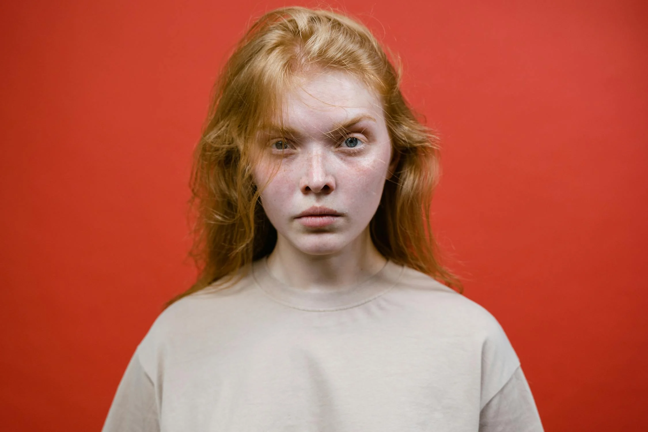 A serious woman on a red backdrop | Source: Pexels