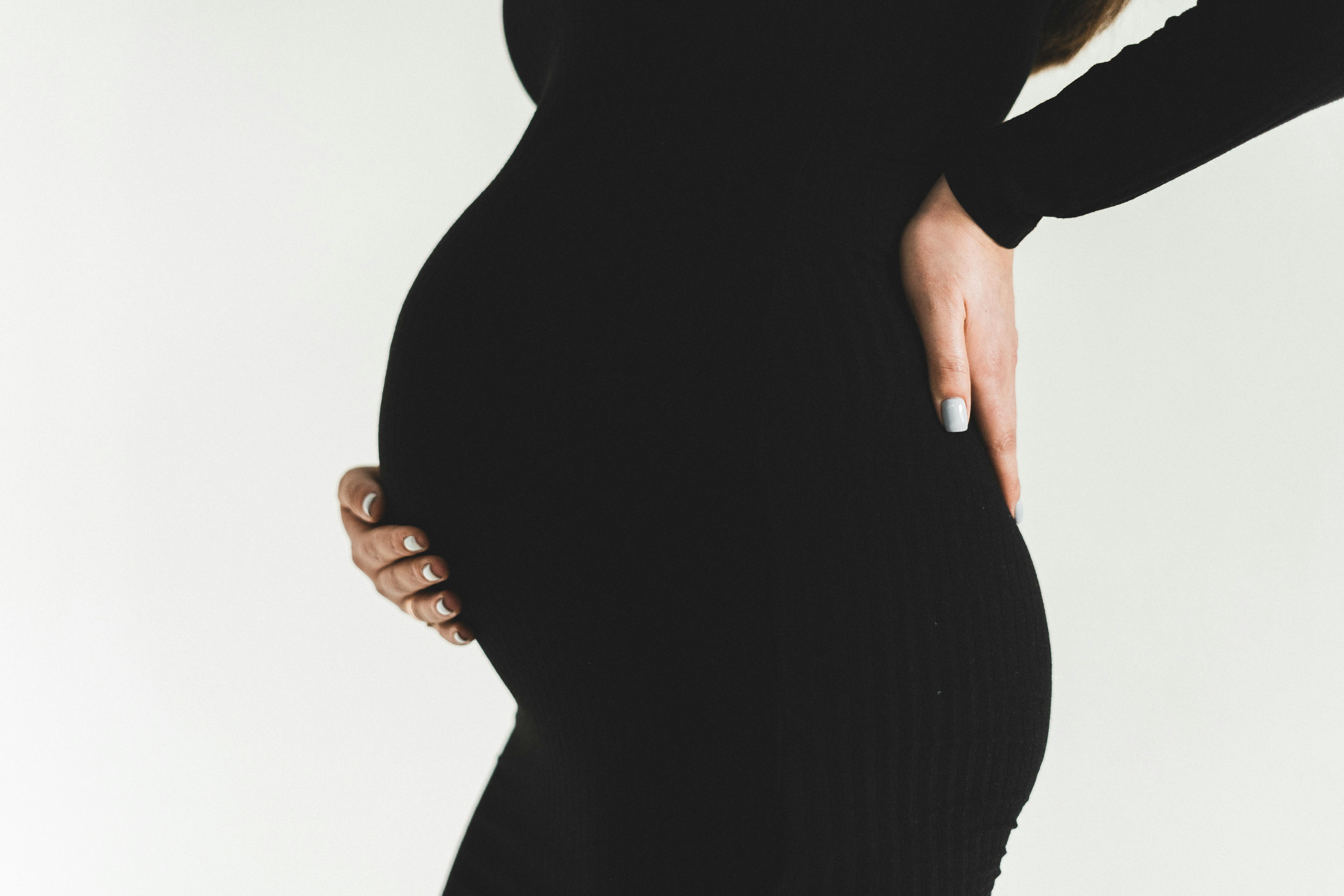 A pregnant woman rubbing her back | Source: Pexels