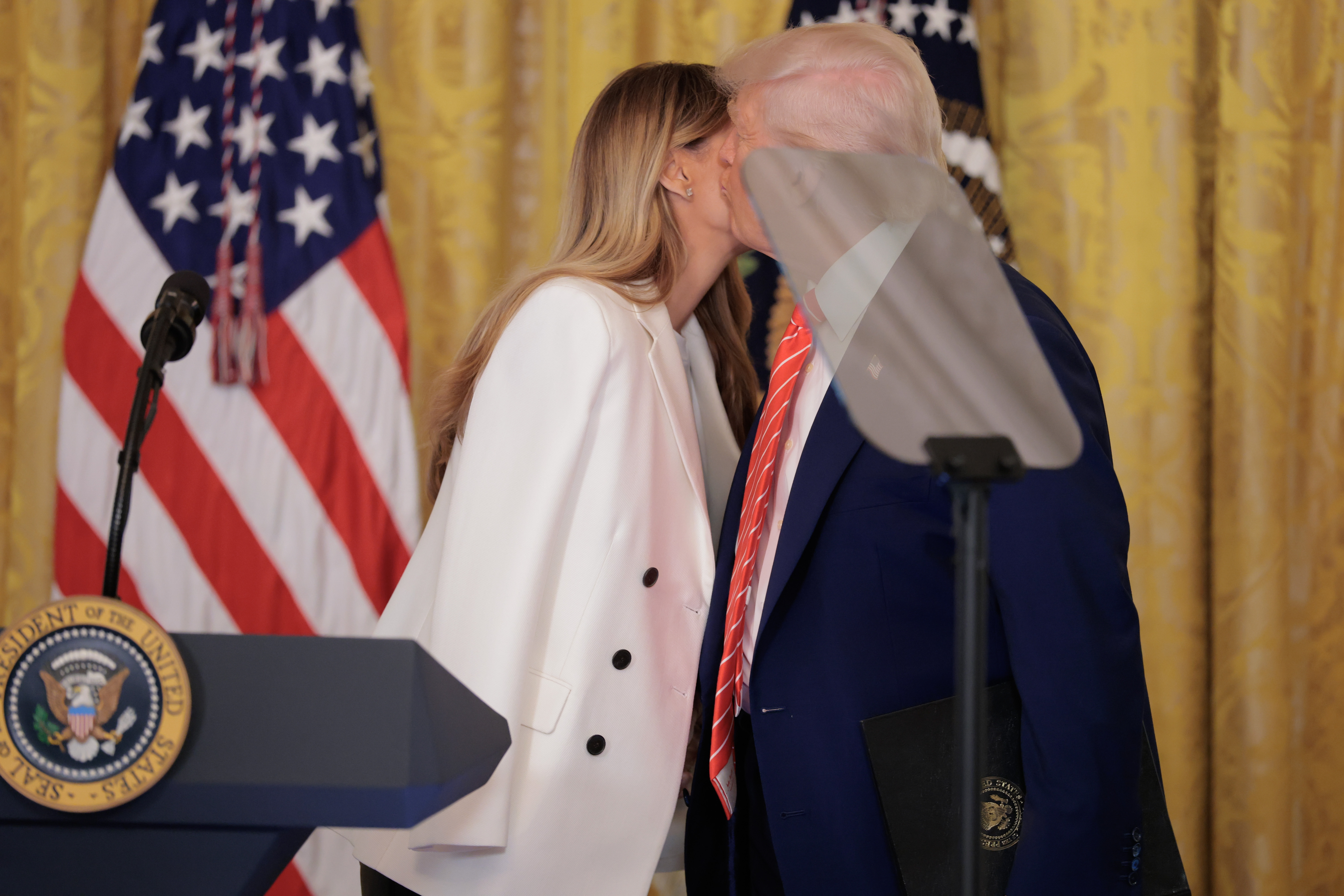 President Donald Trump kisses First Lady Melania Trump during an event to celebrate military mothers in the East Room of the White House on May 8, 2025 in Washington, D.C. | Source: Getty Images