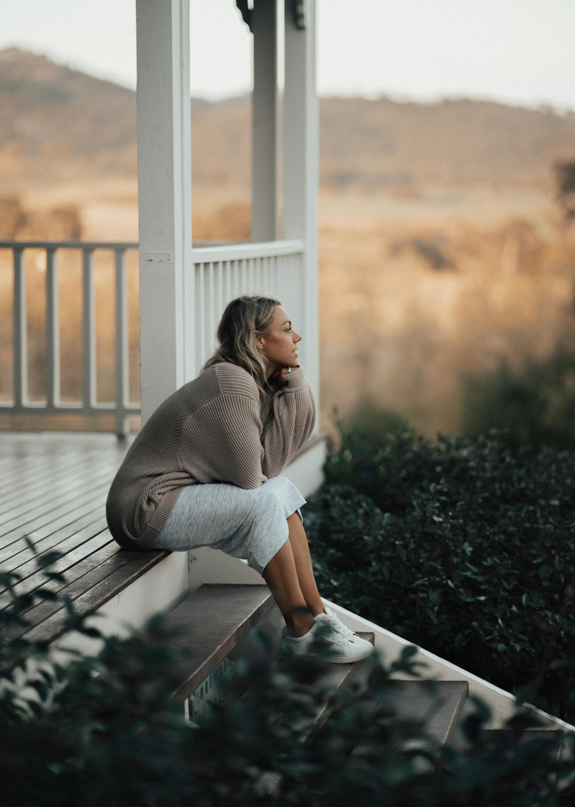 A woman sitting on the front porch of her house | Source: Pexels