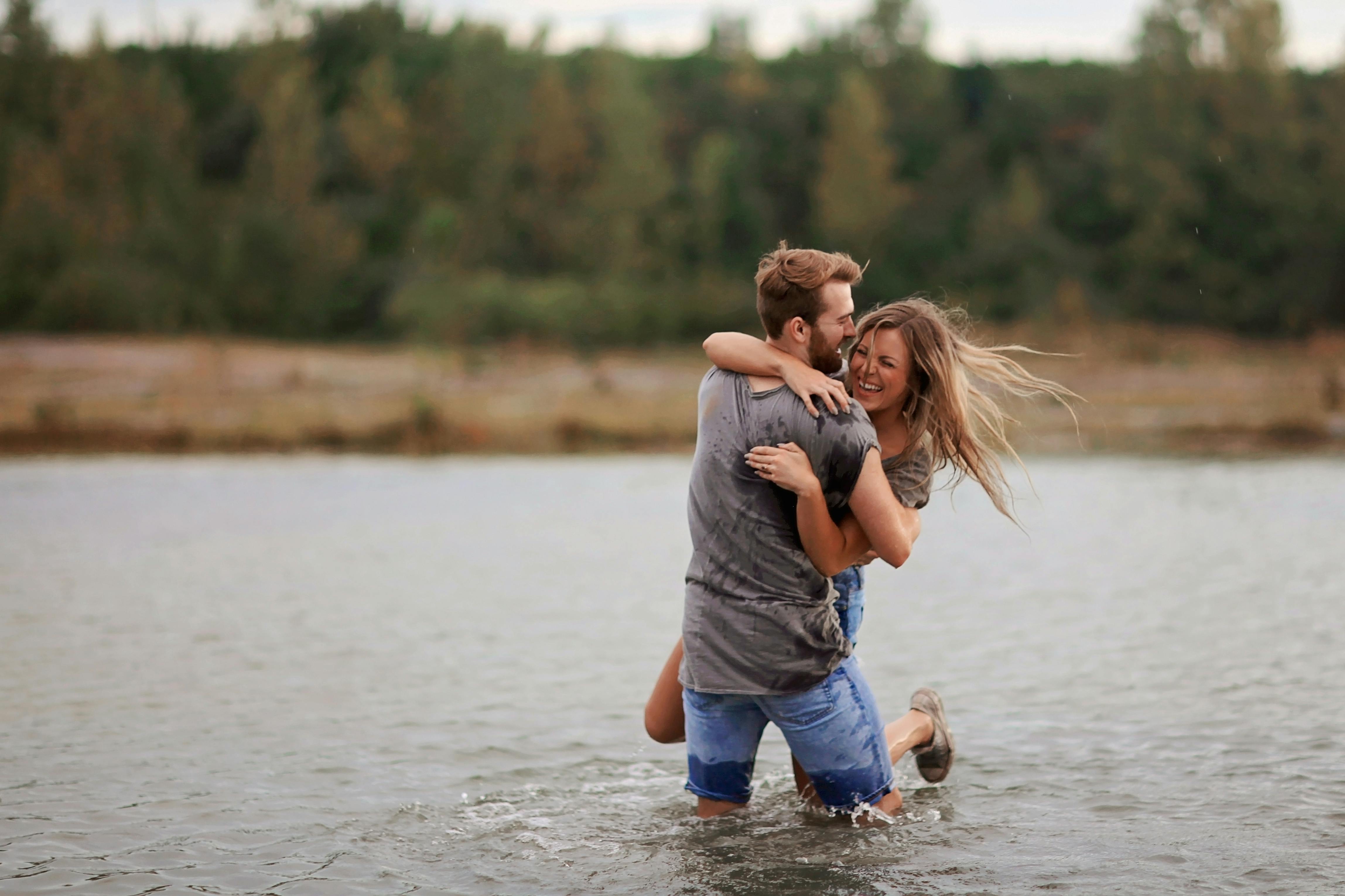 A man hugging a woman while standing in body of water | Source: Pexels