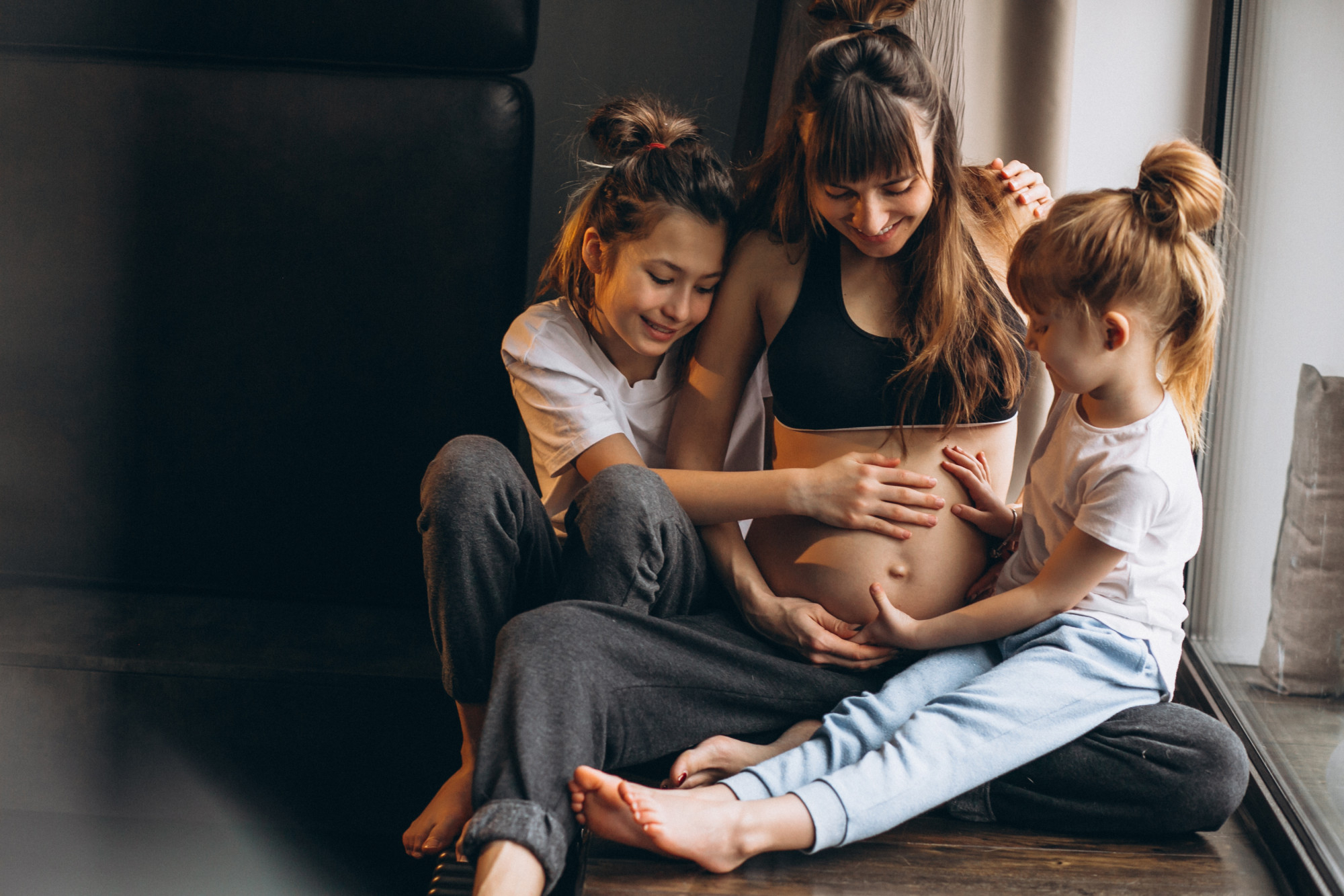 A pregnant woman with children sitting by the window | Source: Freepik