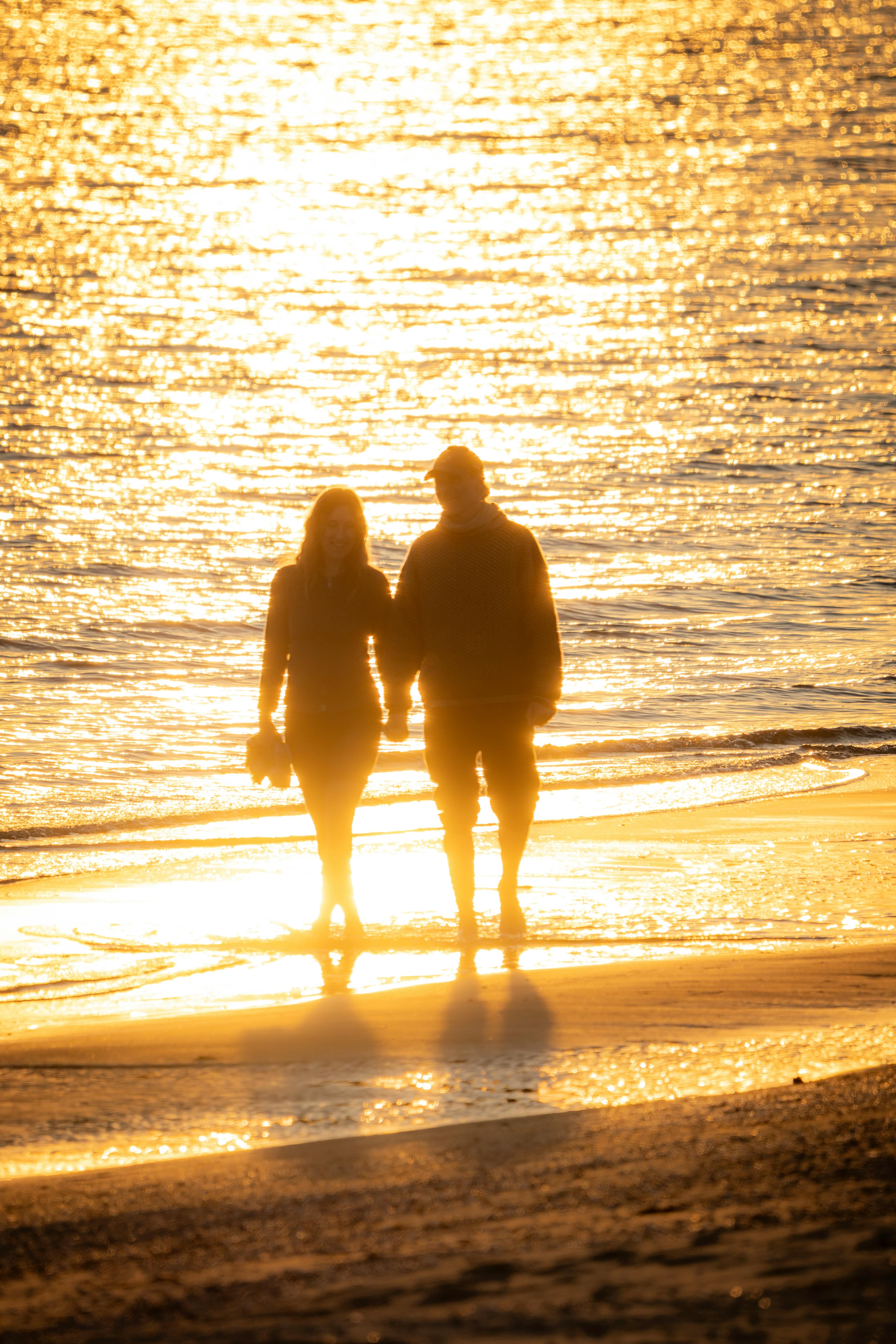 A couple walking on the beach while holding hands | Source: Pexels
