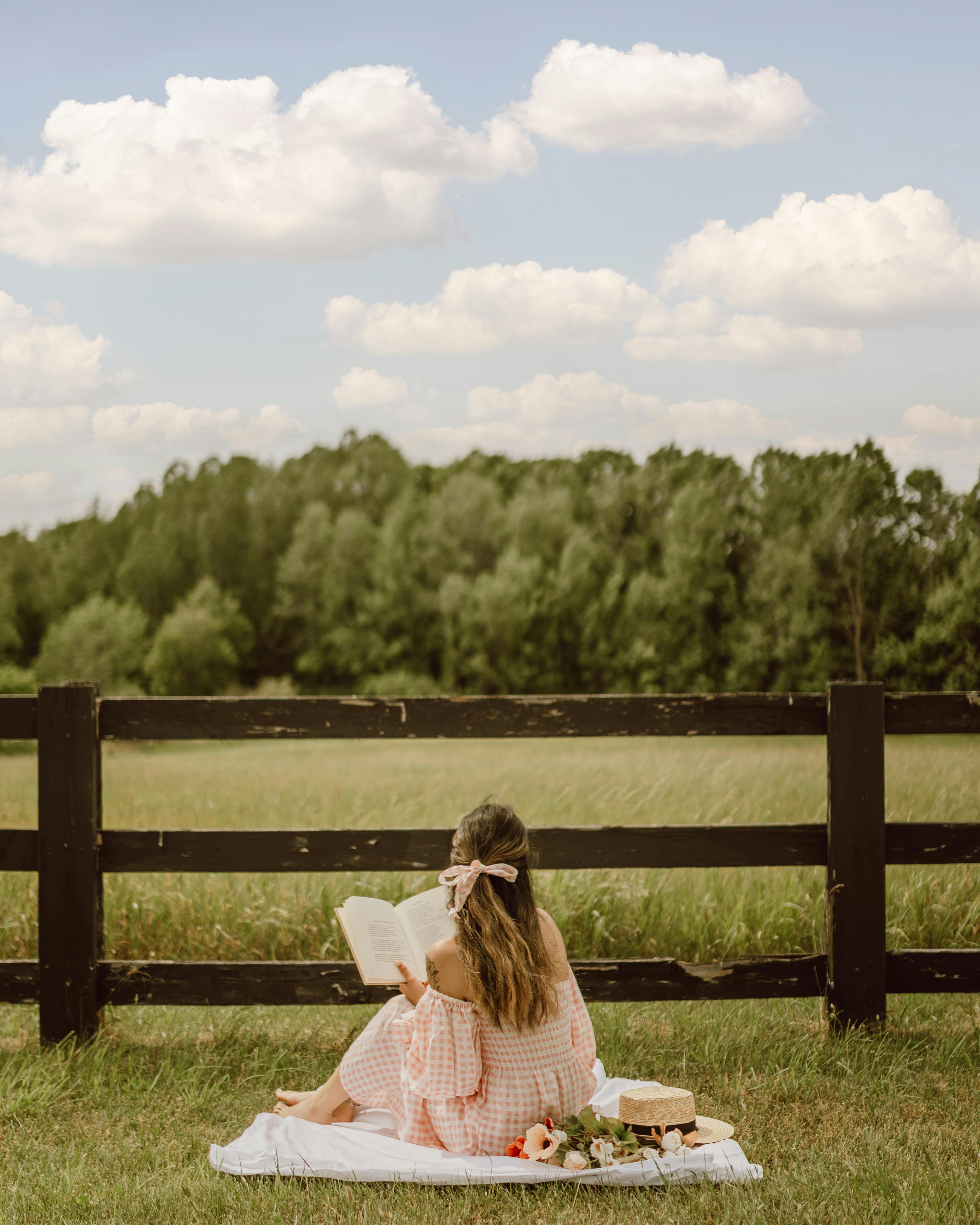 Woman enjoying picnic while reading a book | Source: Pexels