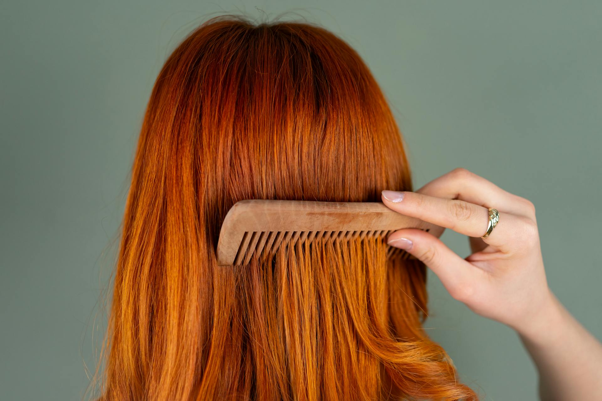 A woman combing her auburn hair | Source: Pexels