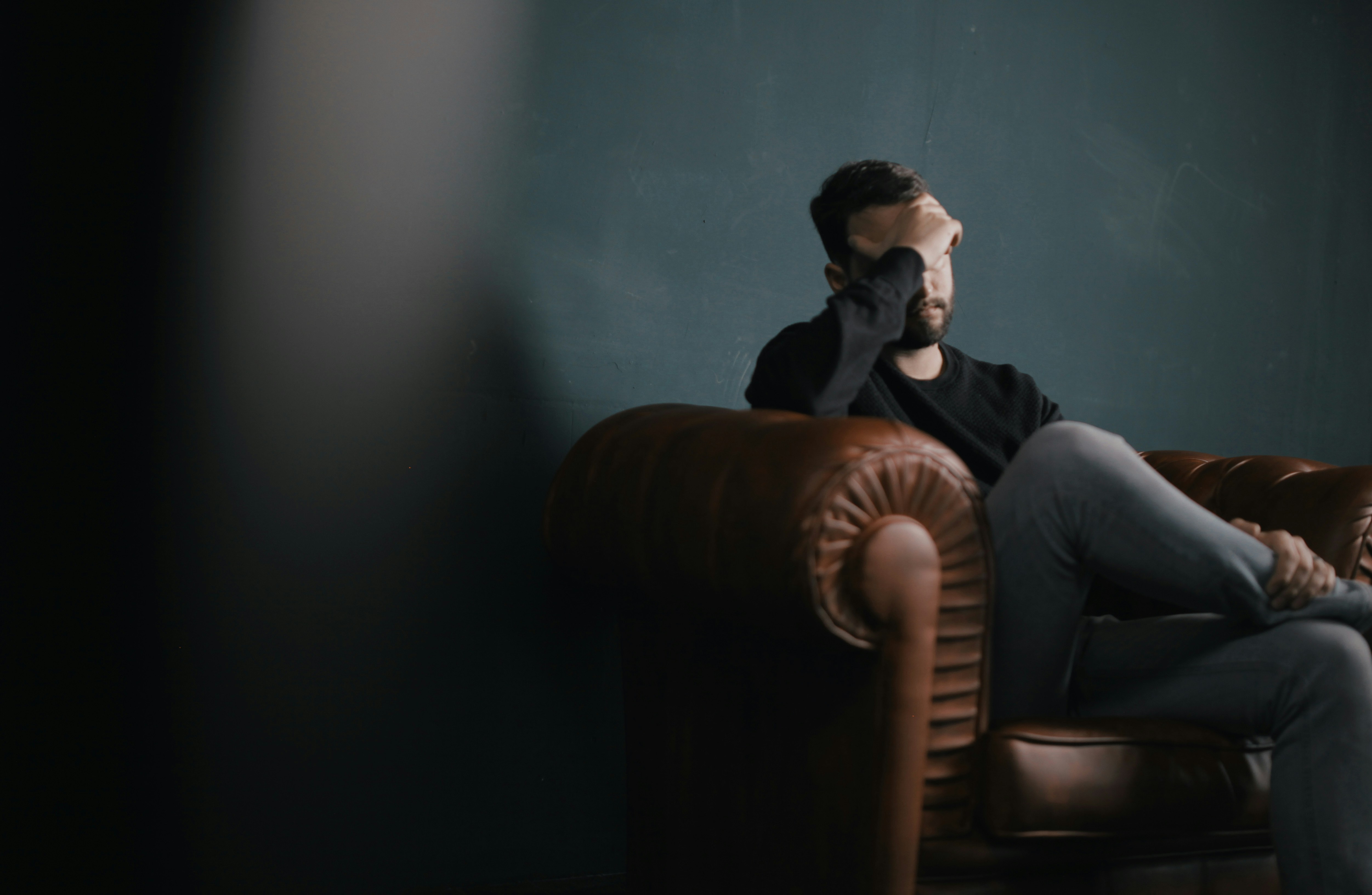 A stressed man sitting on a couch | Source: Unsplash