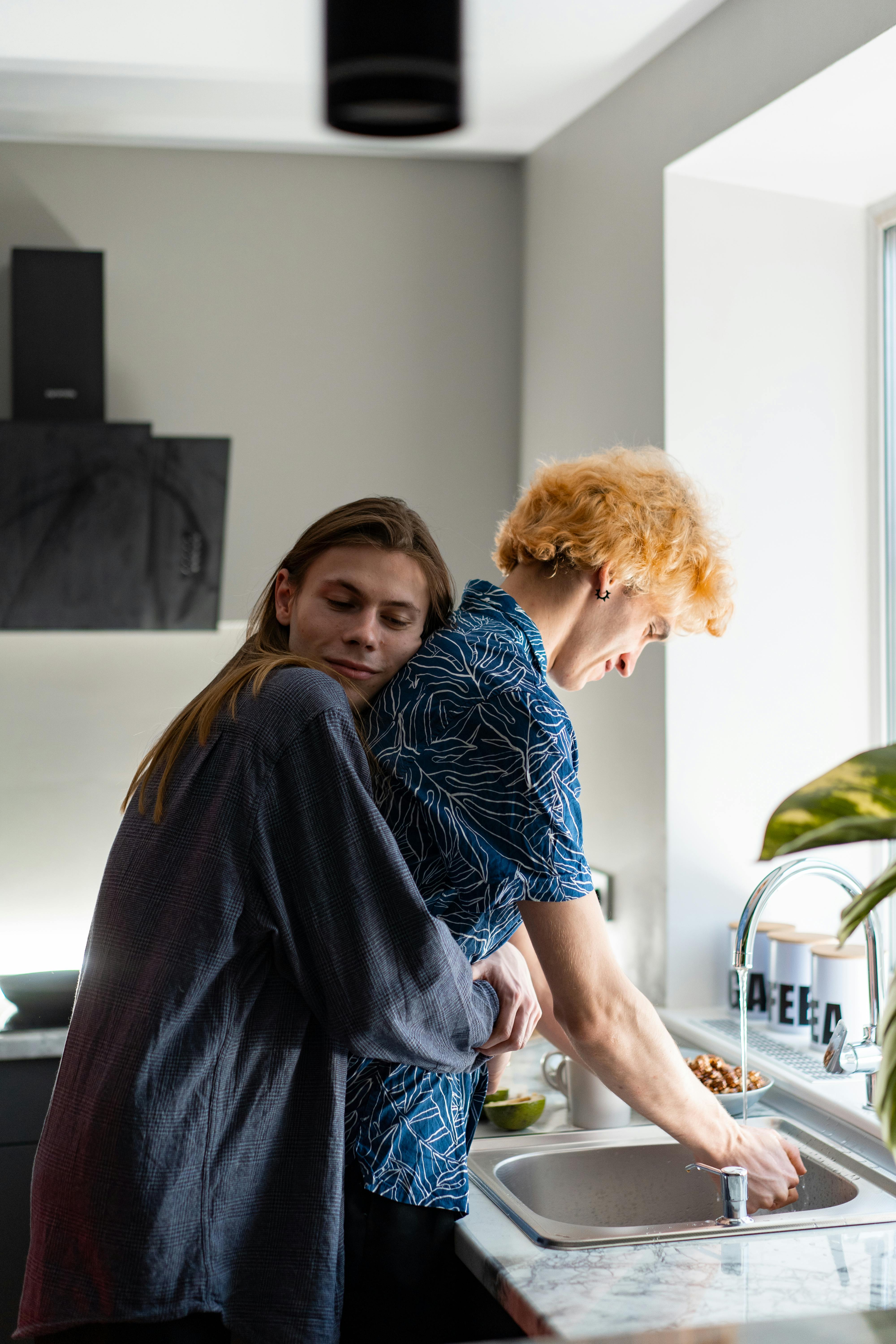 A person hugging a man as he does the dishes | Source: Pexels