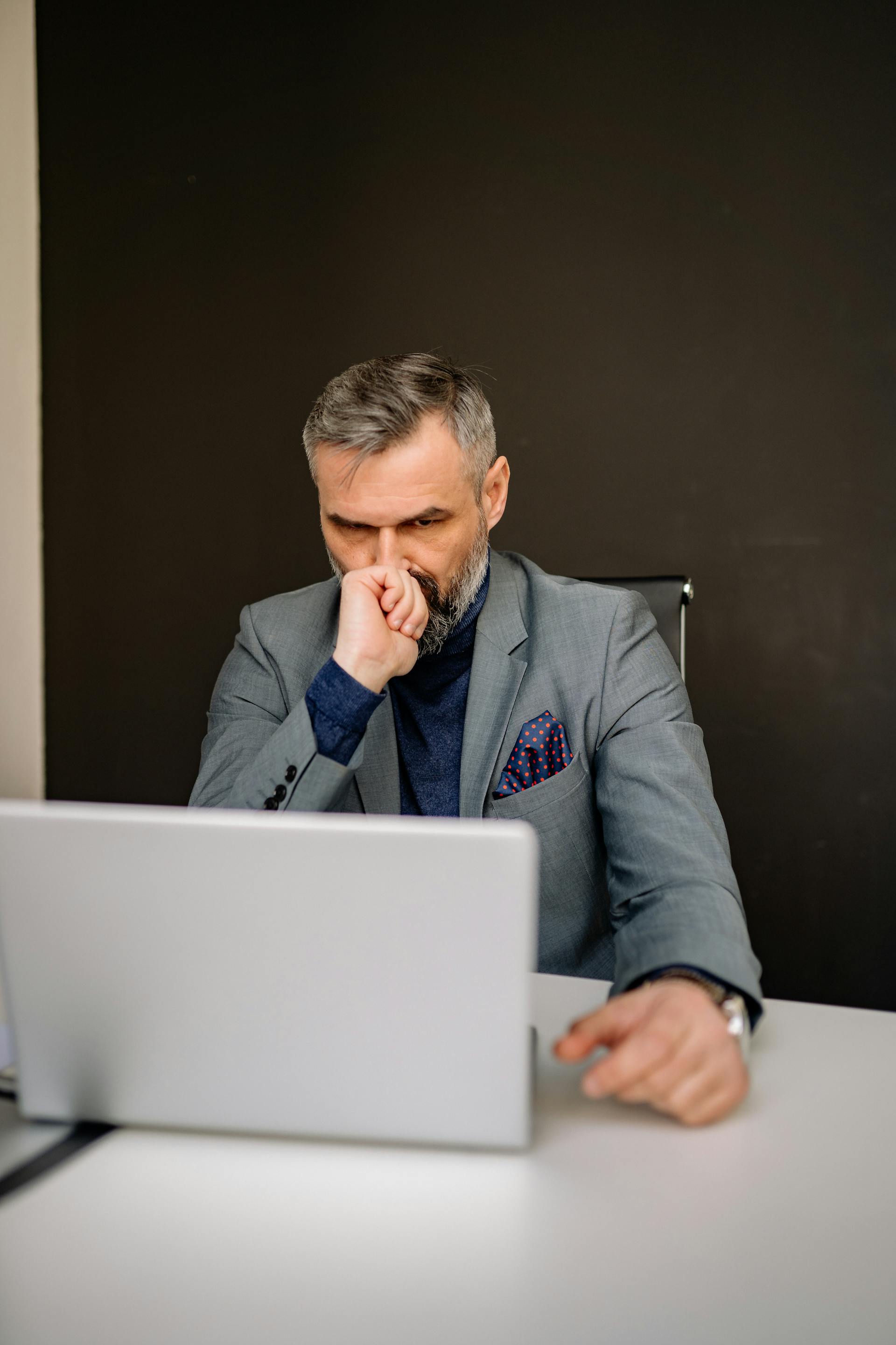 A man looking at his laptop while sitting in the office | Source: Pexels