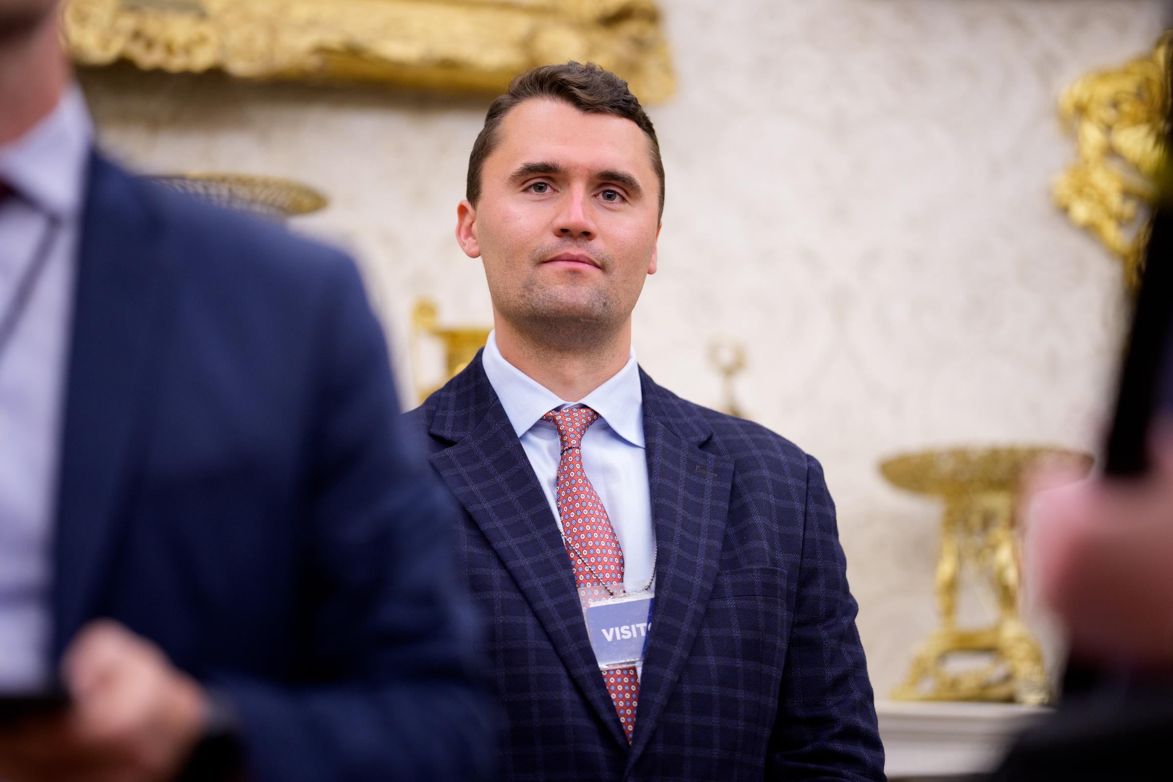 Charlie Kirk stands in the back of the room as US President Donald Trump speaks during a swearing in ceremony for interim US Attorney for Washington, D.C. Jeanine Pirro in the White House on May 28, 2025 in Washington, DC. | Source: Getty Images