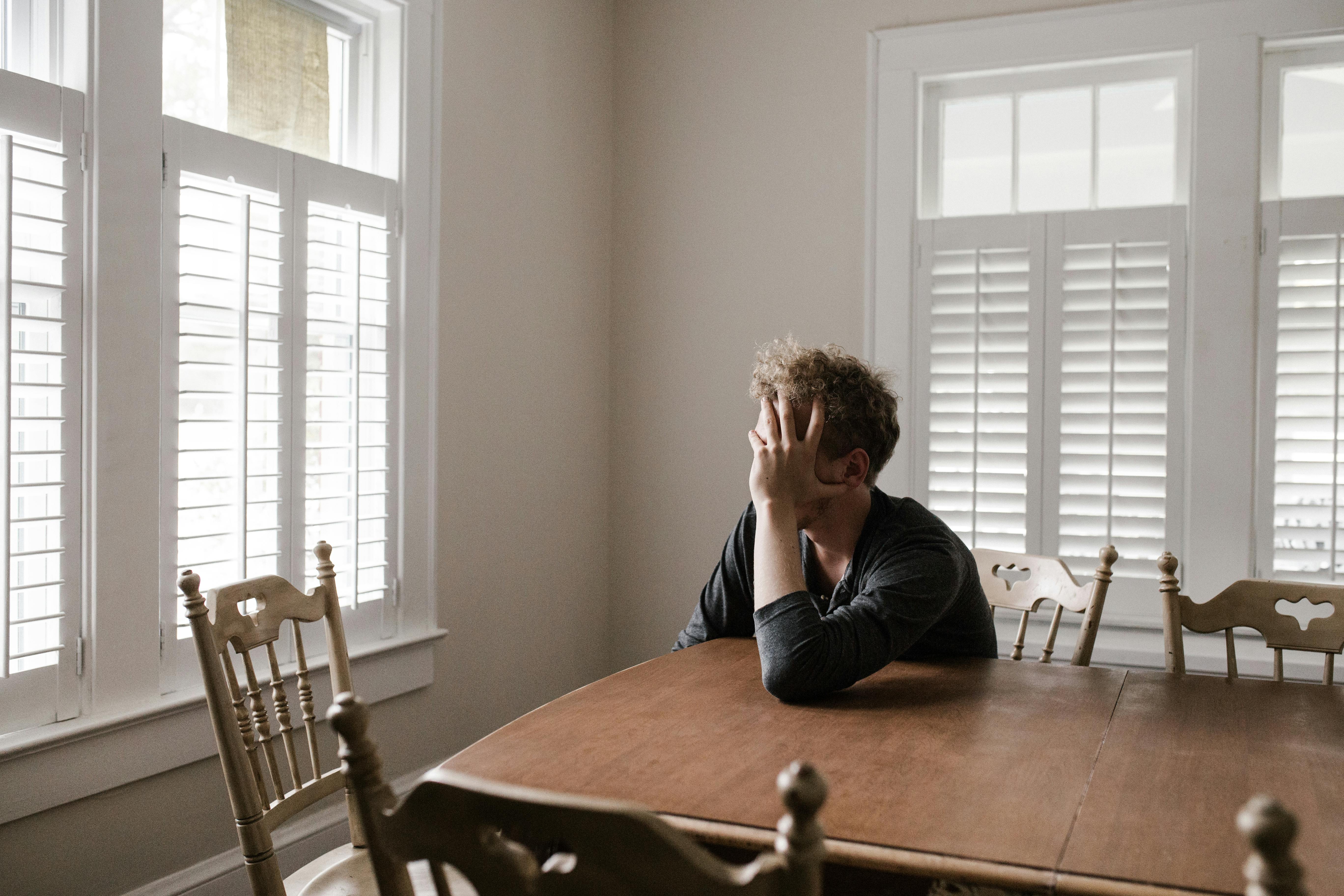 A upset man sitting at a table | Source: Pexels