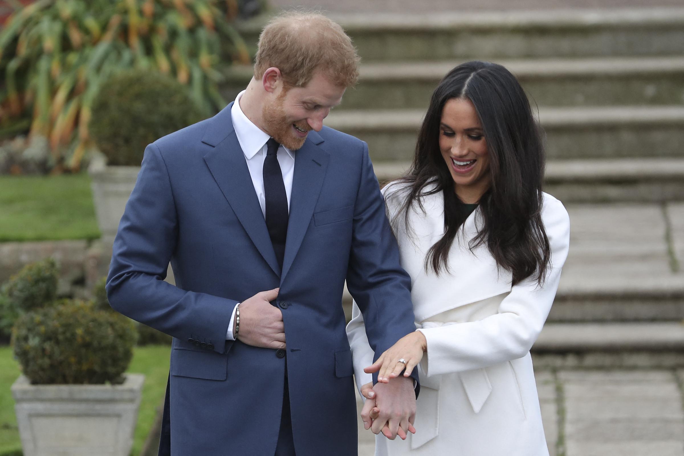 Prince Harry stands with Meghan Markle as she shows off her engagement ring whilst they pose for a photograph in the Sunken Garden at Kensington Palace on November 27, 2017, in West London. | Source: Getty Images