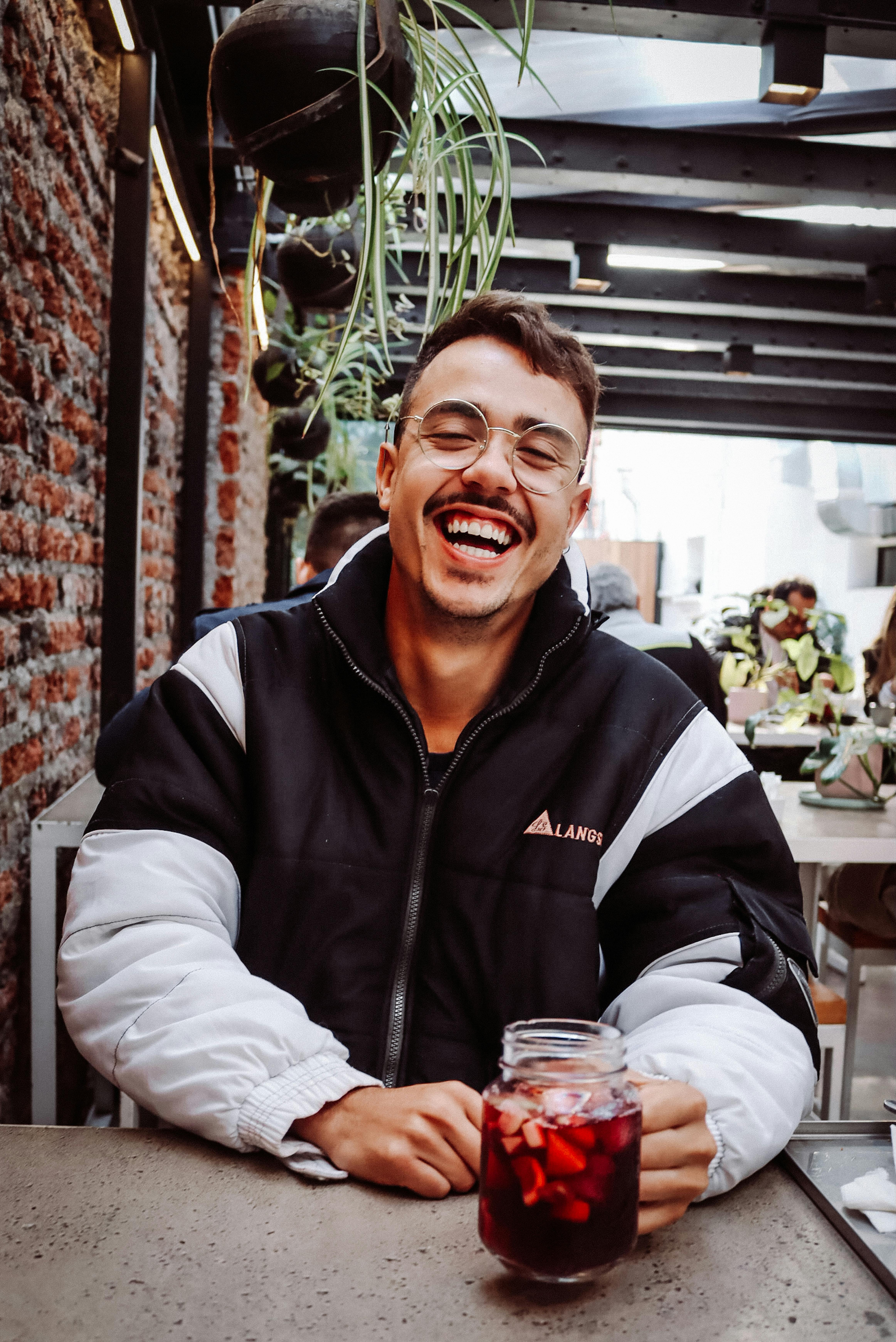 A man laughing while holding a drink in a jar | Source: Pexels