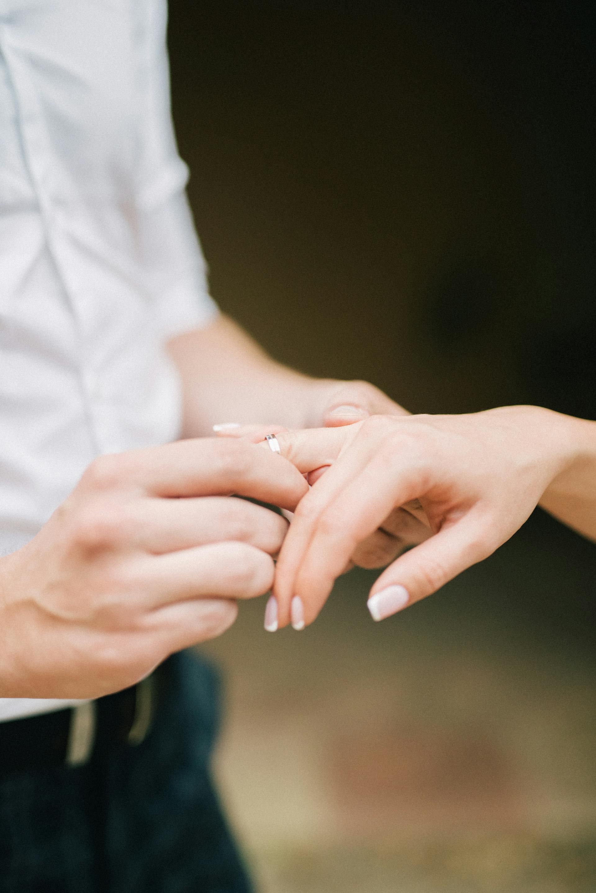 A man sliding a ring onto a woman's finger | Source: Pexels