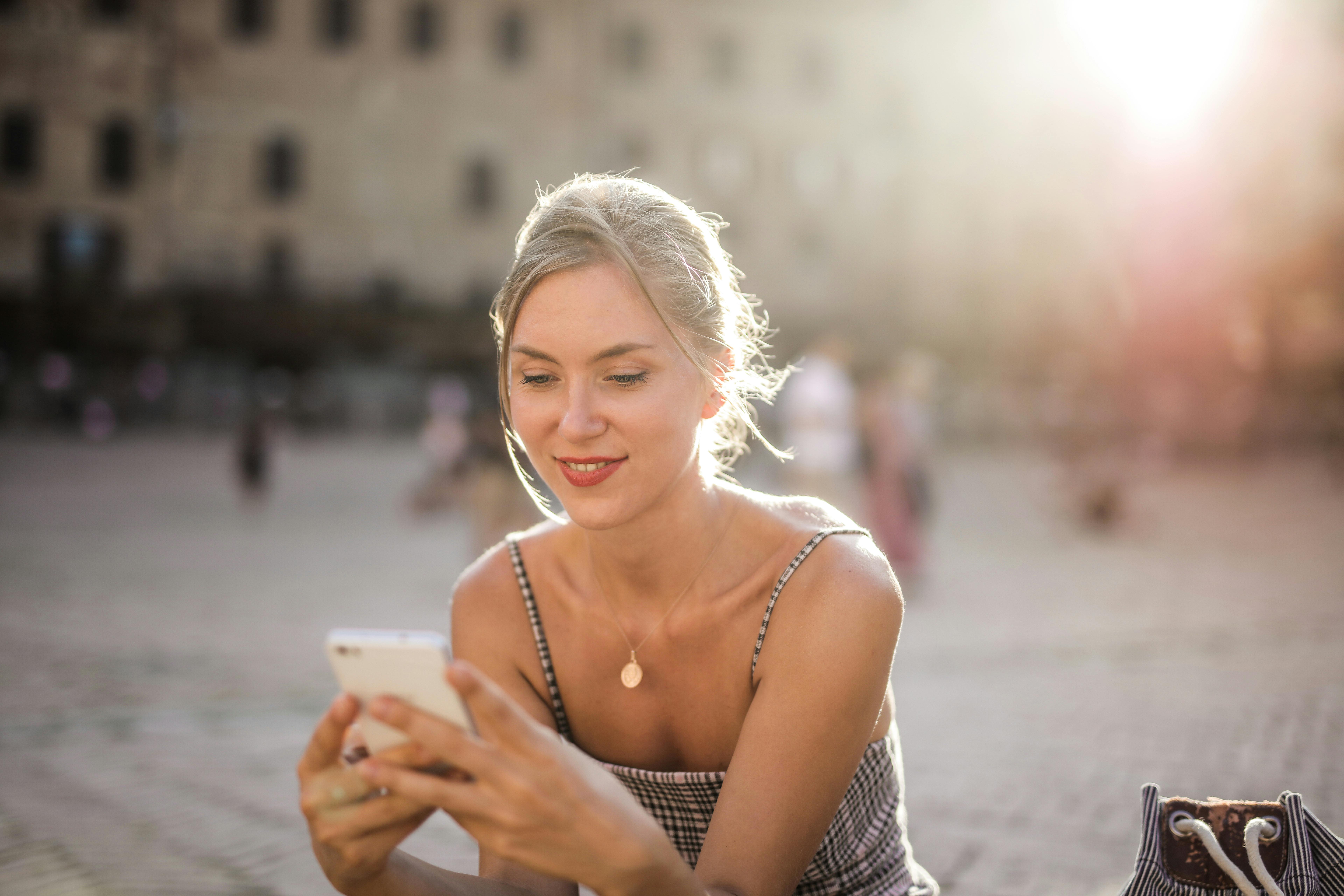 A happy woman using her phone | Source: Pexels