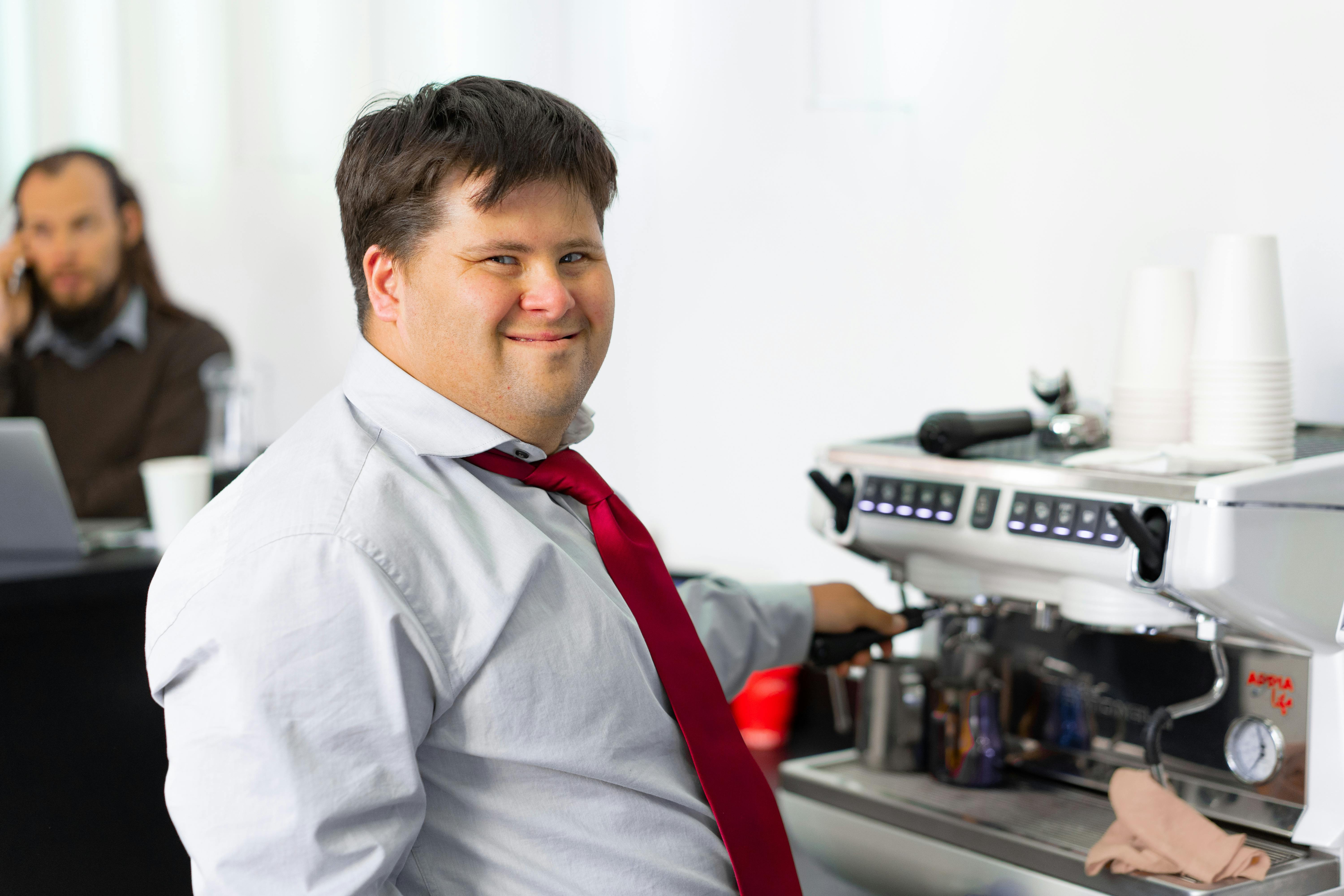 A man smiling while standing at a coffee machine | Source: Pexels
