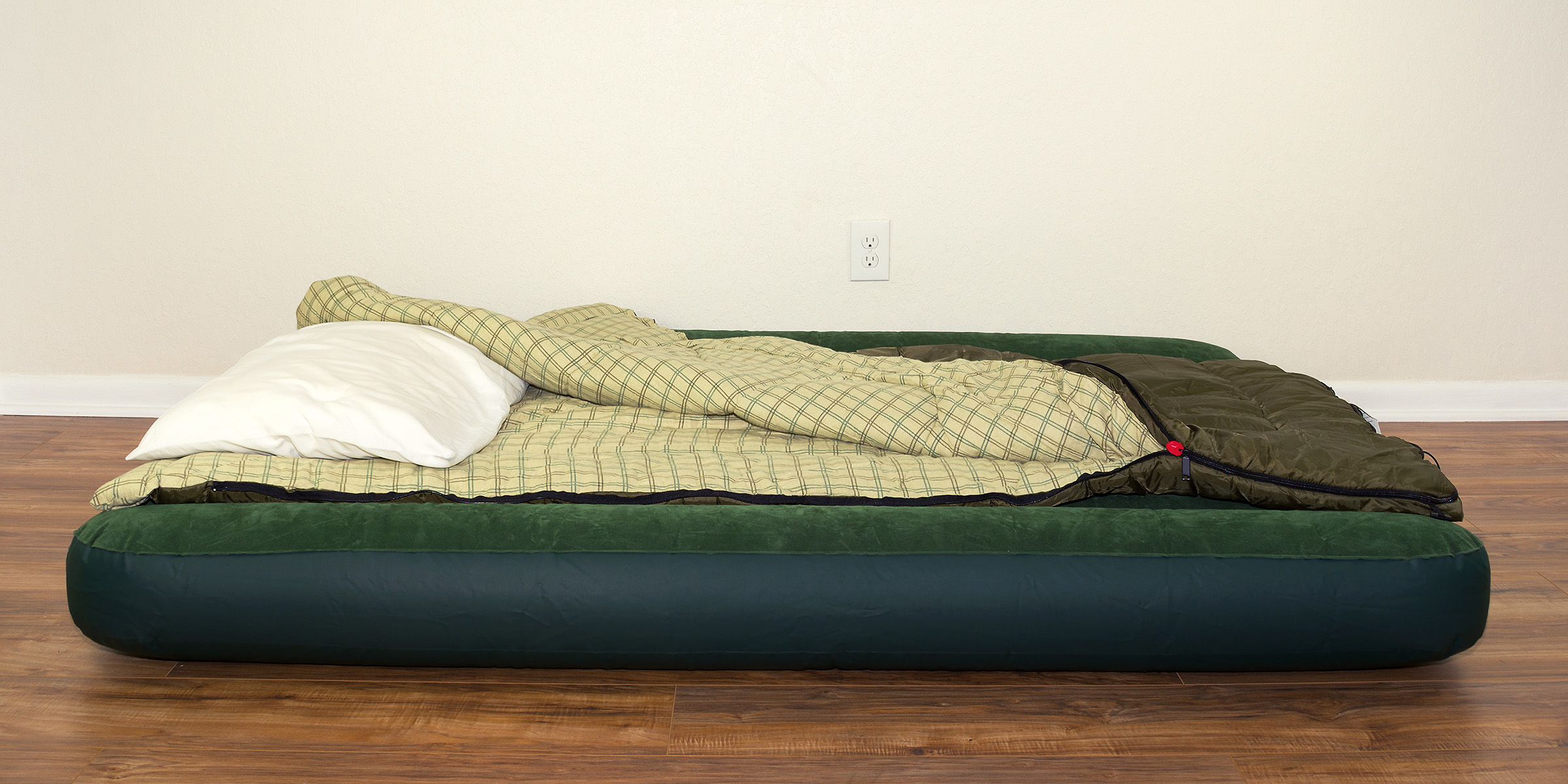 An air mattress with a sleeping bag and pillow laid out on a hardwood floor | Source: Shutterstock