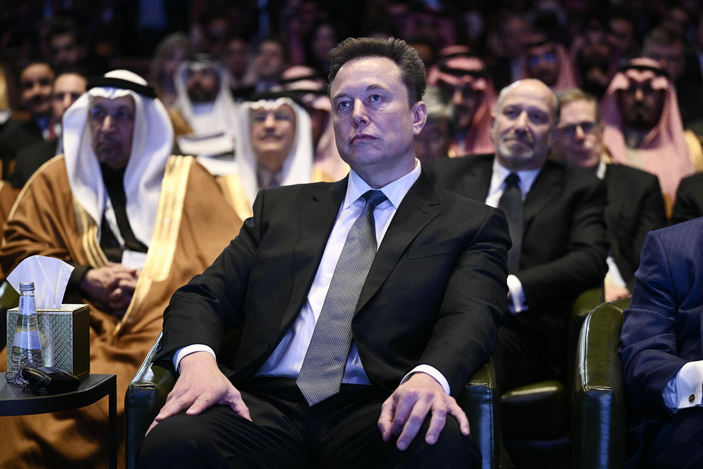 Elon Musk looks on as US President Donald Trump speaks at the US-Saudi Investment Forum at the John F. Kennedy Center for the Performing Arts in Washington, DC on November 19, 2025. | Source: Getty Images