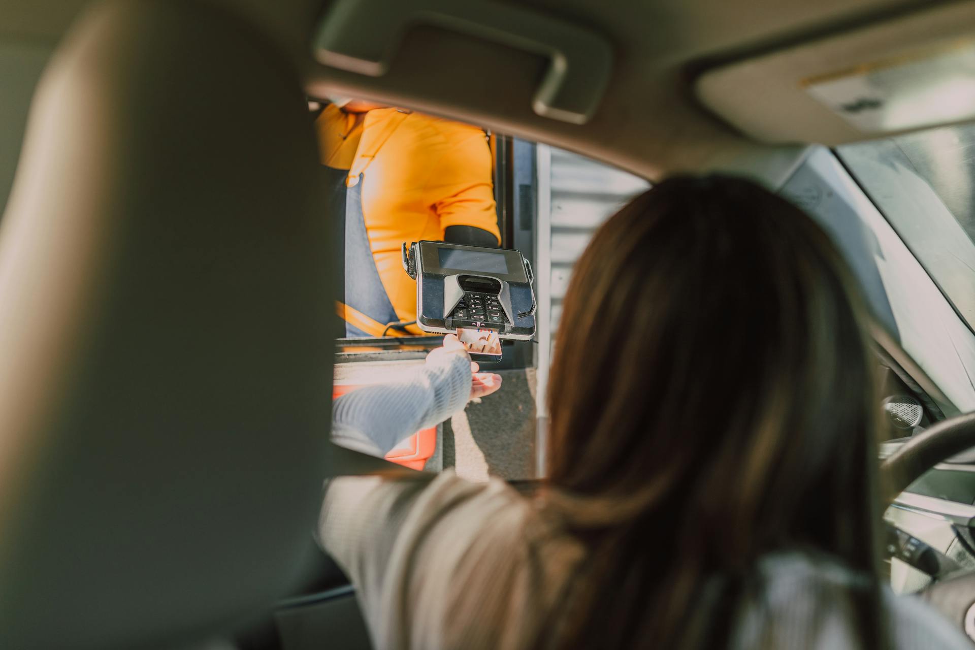 A woman sitting in her car and making a payment at a drive-through | Source: Pexels