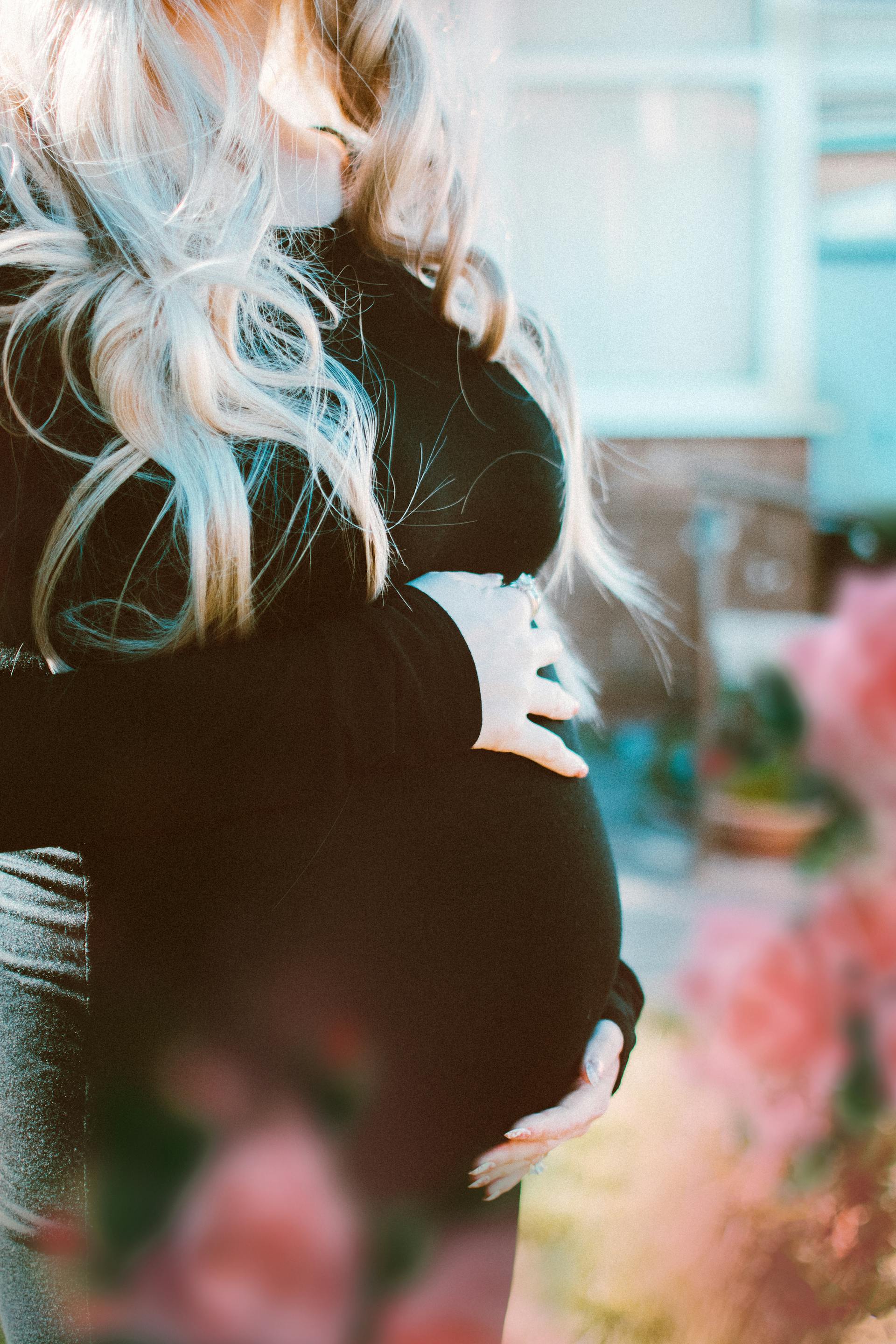 A pregnant woman holding her baby bump outdoors | Source: Pexels