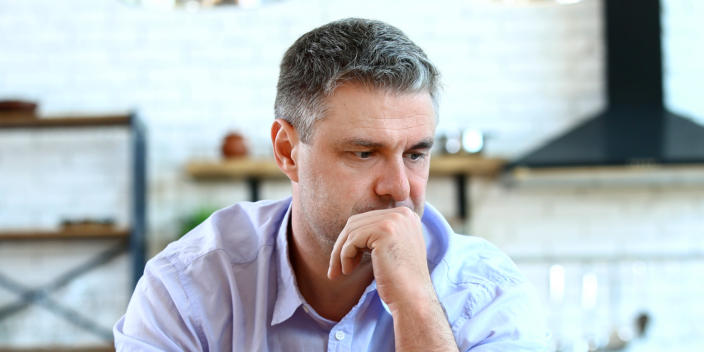A pensive man sitting at a table | Source: Shutterstock