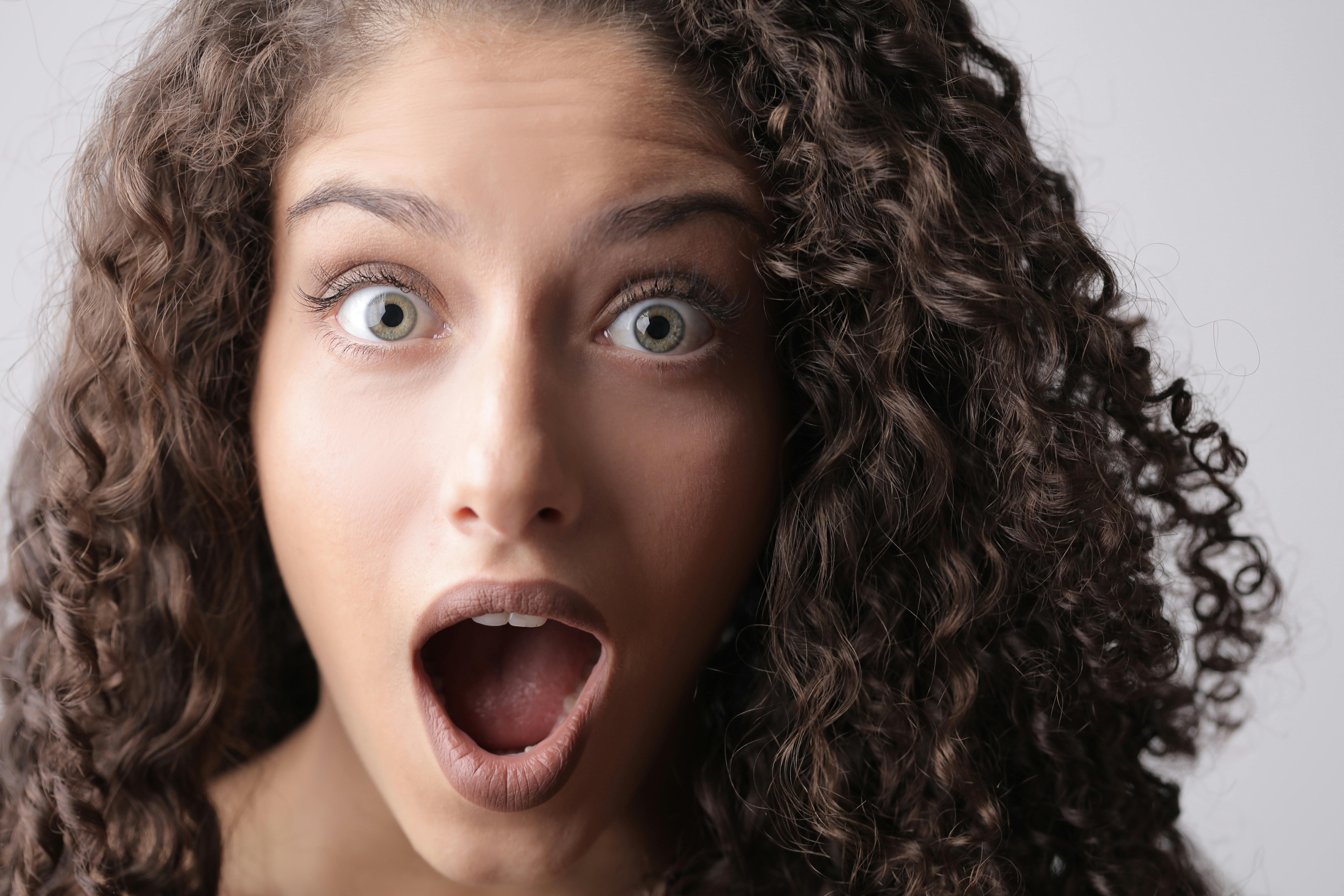Uma mulher chocada com cabelos castanhos cacheados | Fonte: Pexels