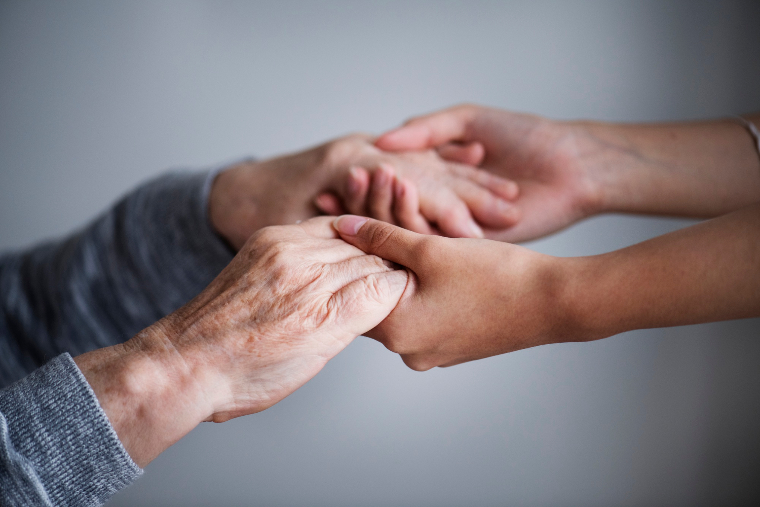 A young woman holding an older woman's hands offering support and assurance | Source: Freepik