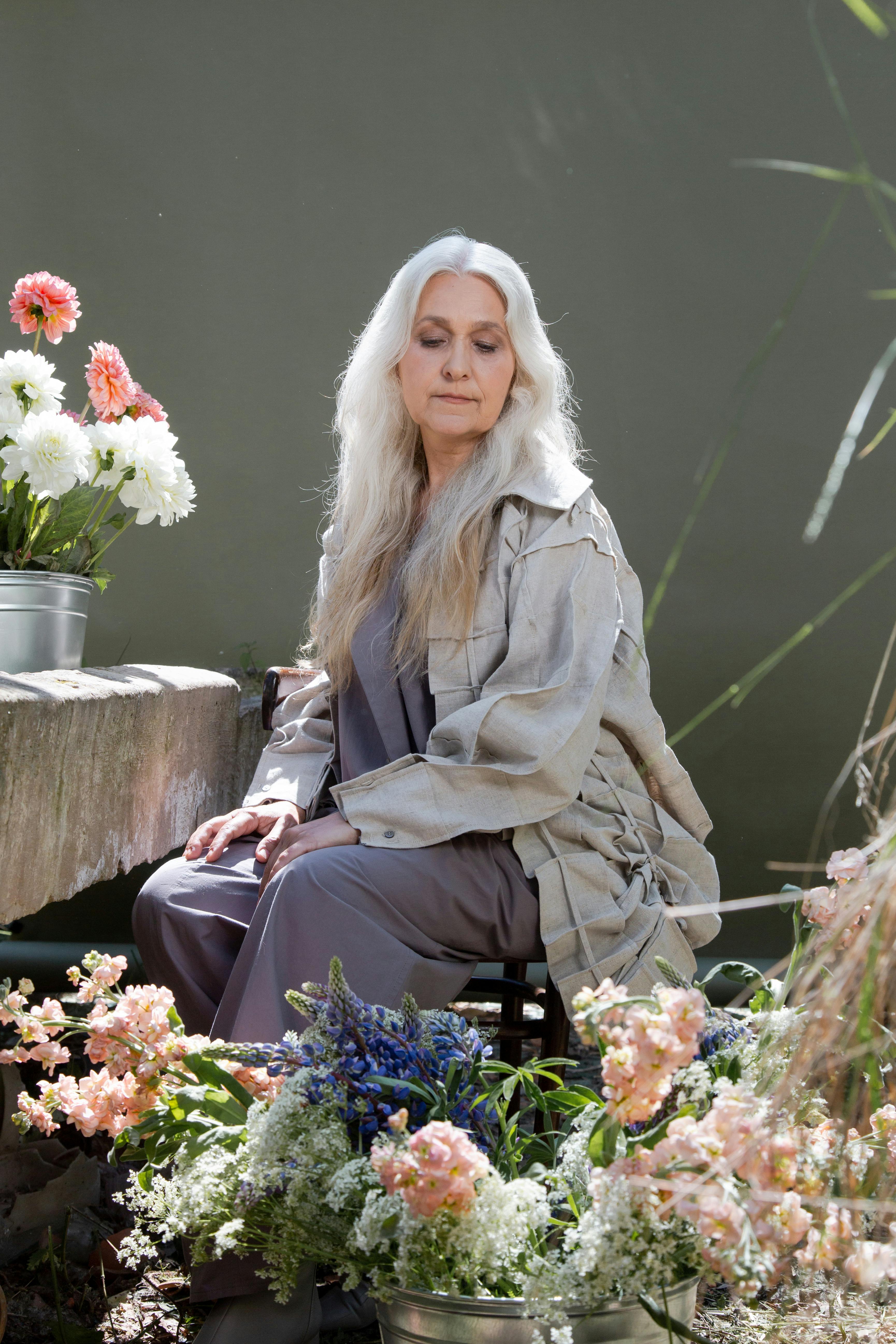 An older woman sitting with flowers | Source: Pexels