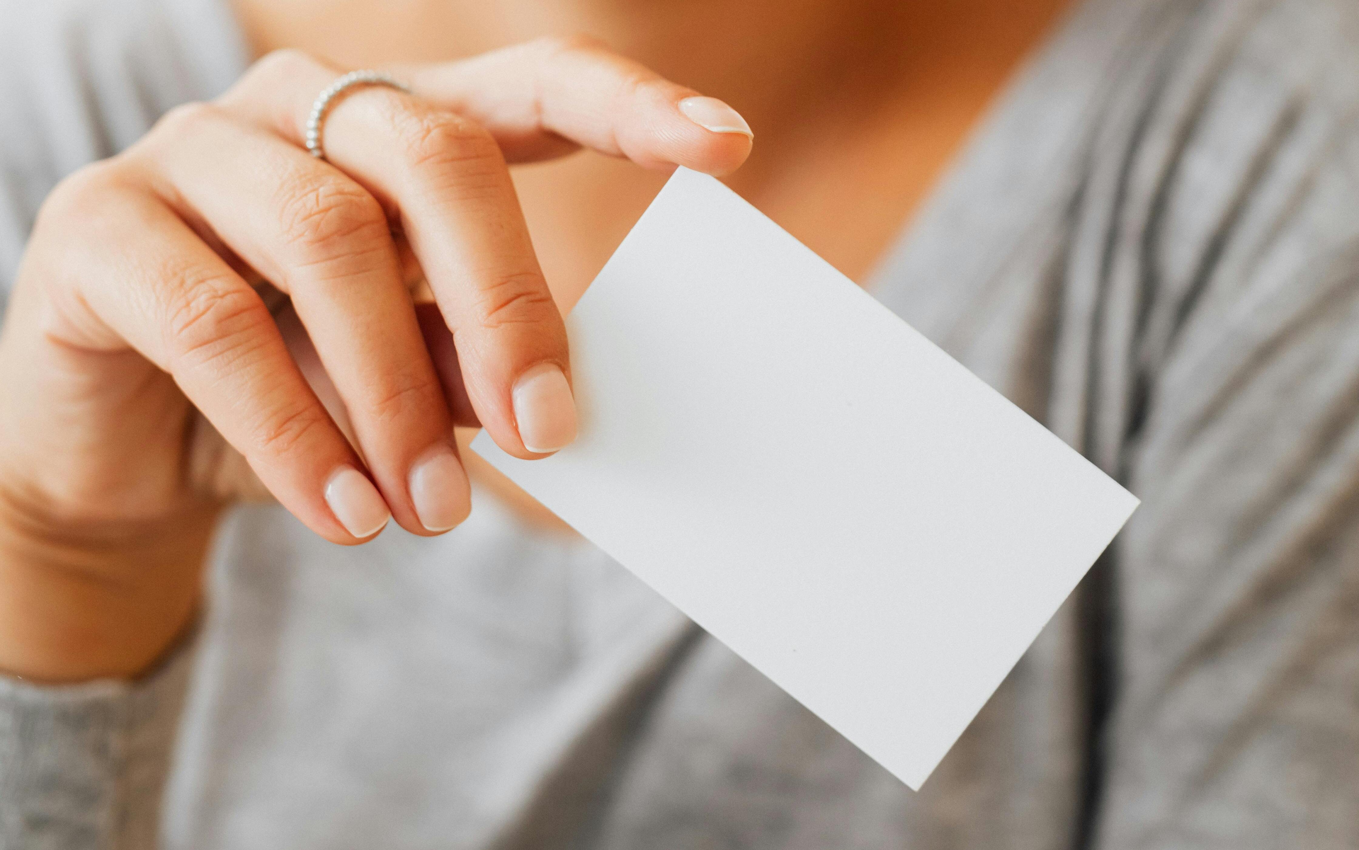 A woman hands over a business card | Source: Pexels