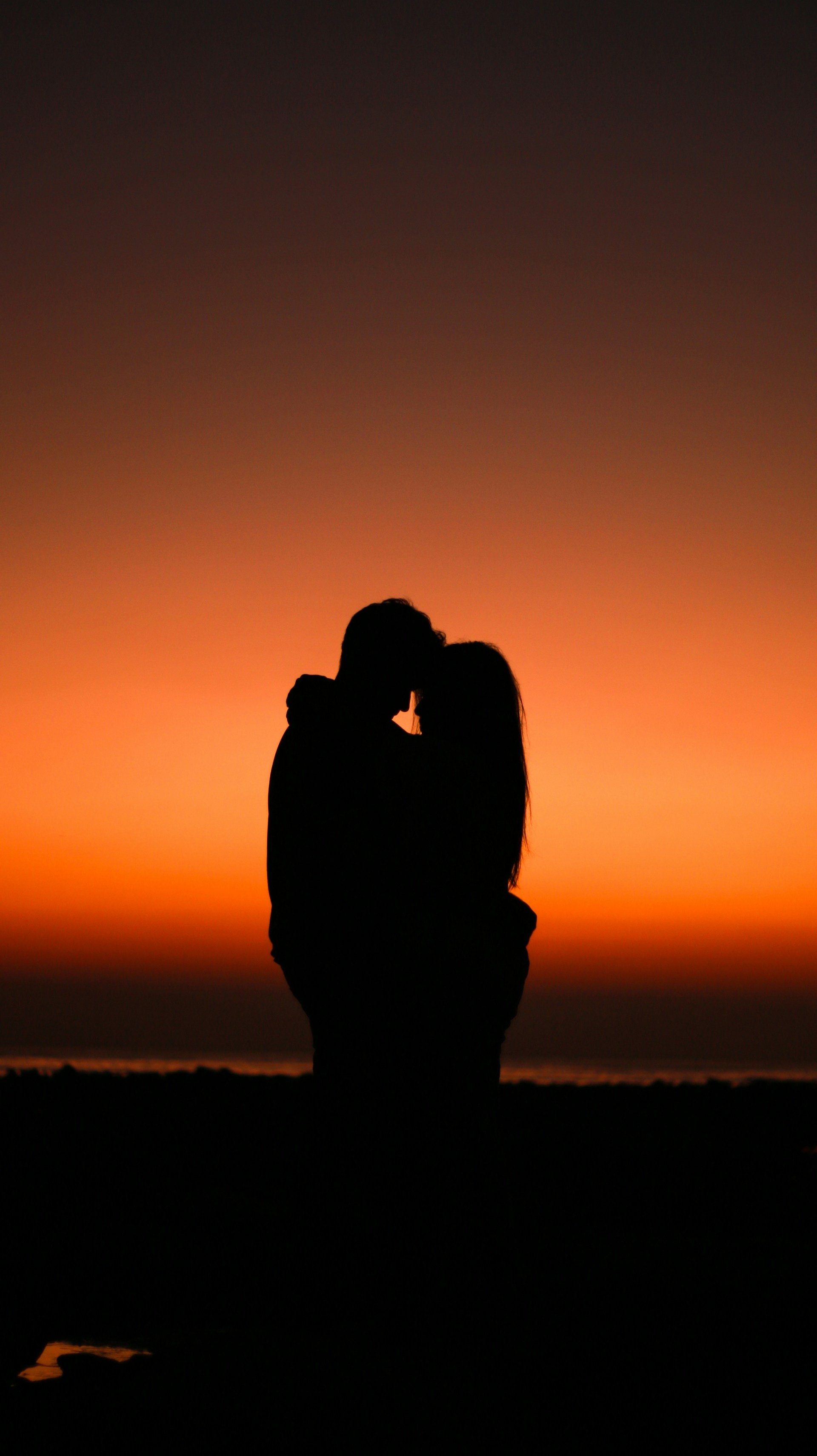 Silhouette of a couple hugging on a golden evening | Source: Unsplash