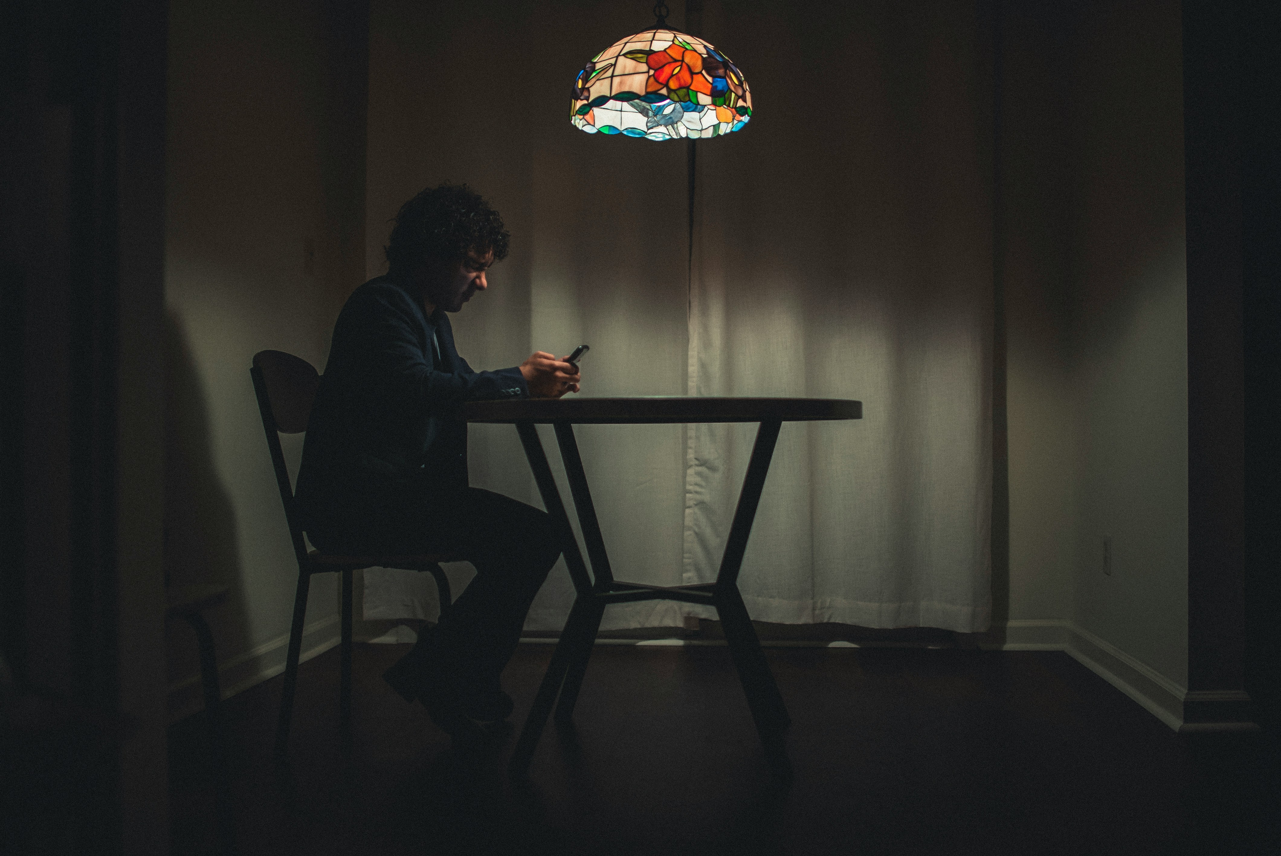 A man sitting at a table and using a cellphone | Source: Unsplash
